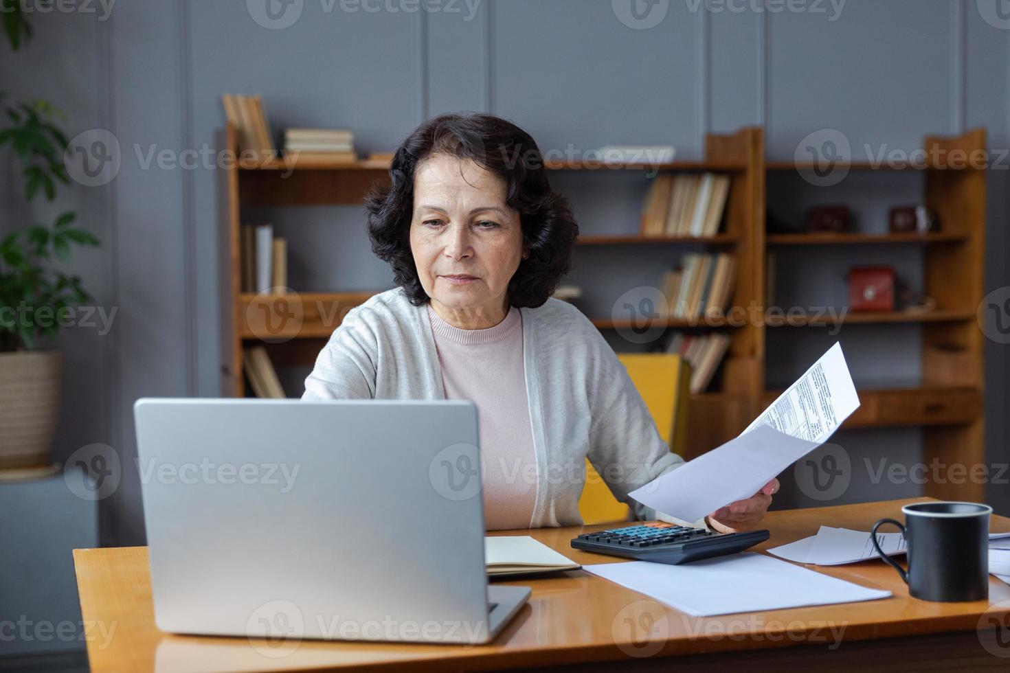 Mitte alt Senior Frau sitzen mit Laptop und Papier dokumentieren, nachdenklich älter reifen Dame lesen Papier Rechnung Zahlen online beim Zuhause Verwaltung Bank Finanzen rechnen Steuern Planung Darlehen Schuld die Pension Zahlung foto