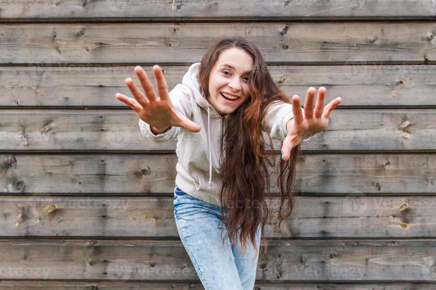 glückliches Mädchen lächelt. Schönheitsporträt junge glückliche positive lachende brünette Frau auf Holzwandhintergrund foto