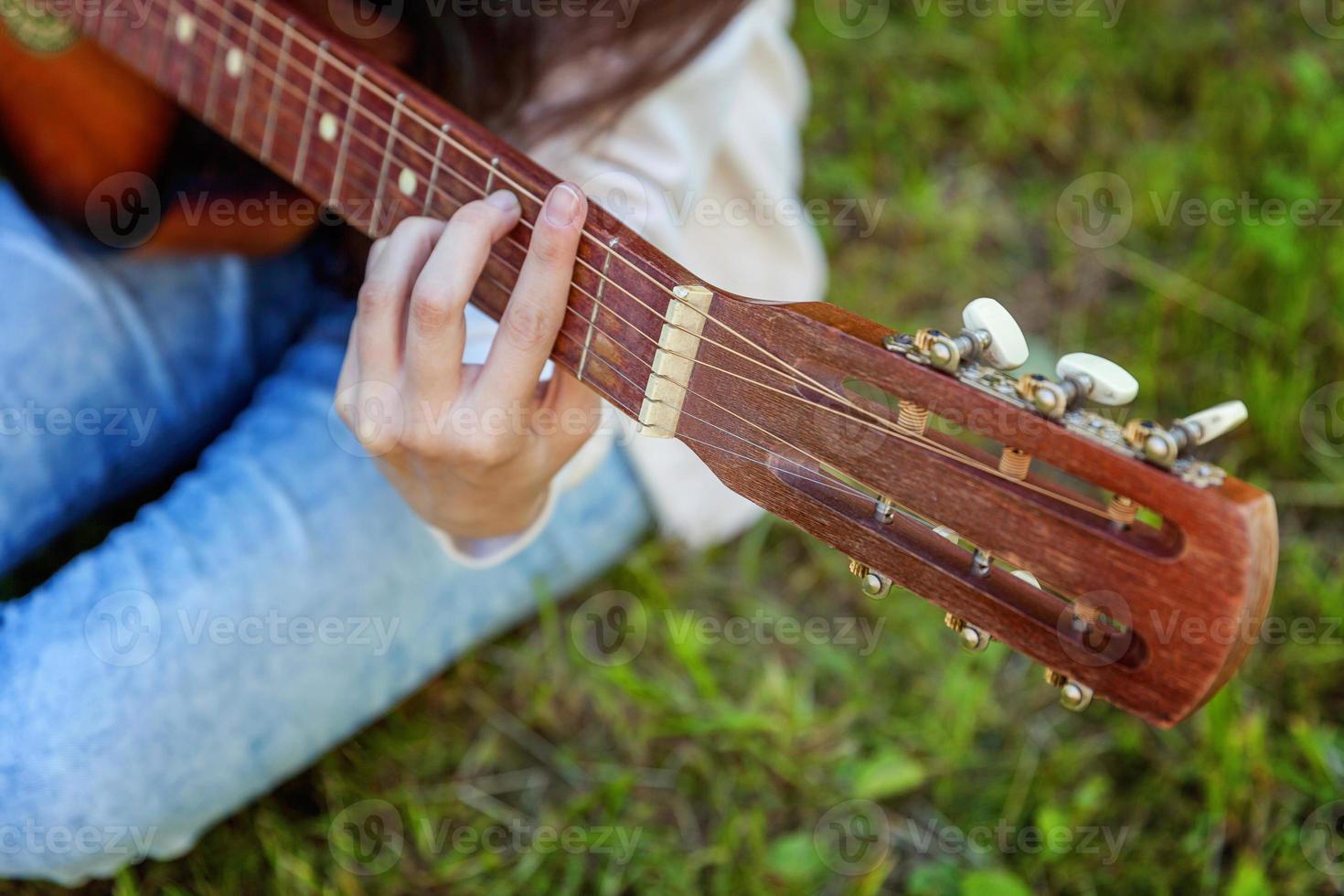 frauenhände, die akustikgitarre spielen foto