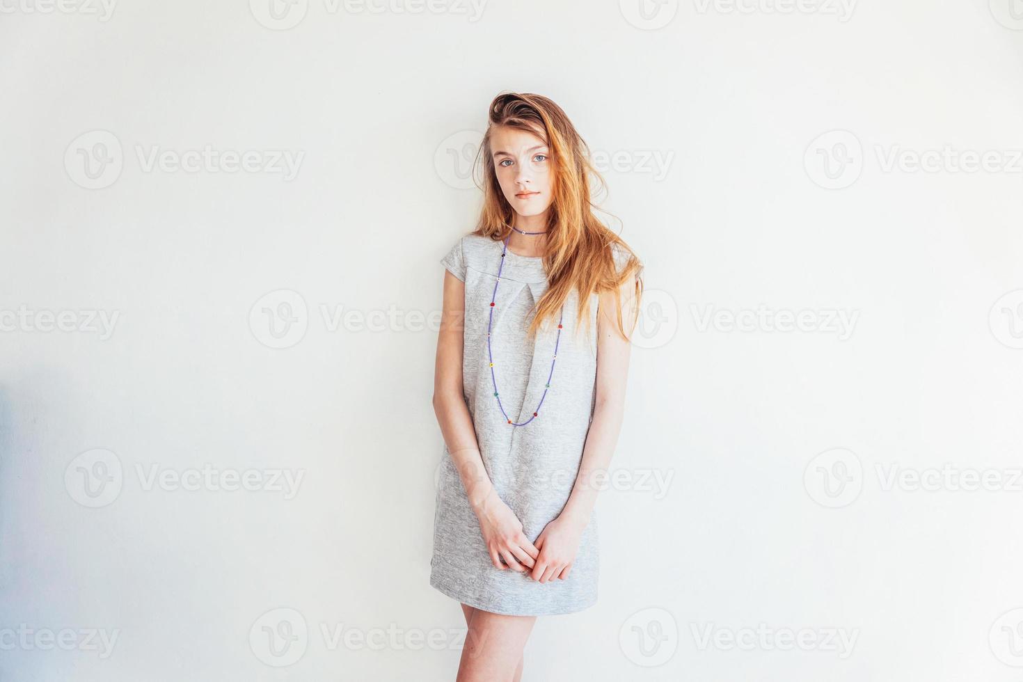 Schönheit Teenager Mädchen. Porträt jung Teen Frau im grau Kleid gegen Weiß Mauer Hintergrund. europäisch Frau. foto