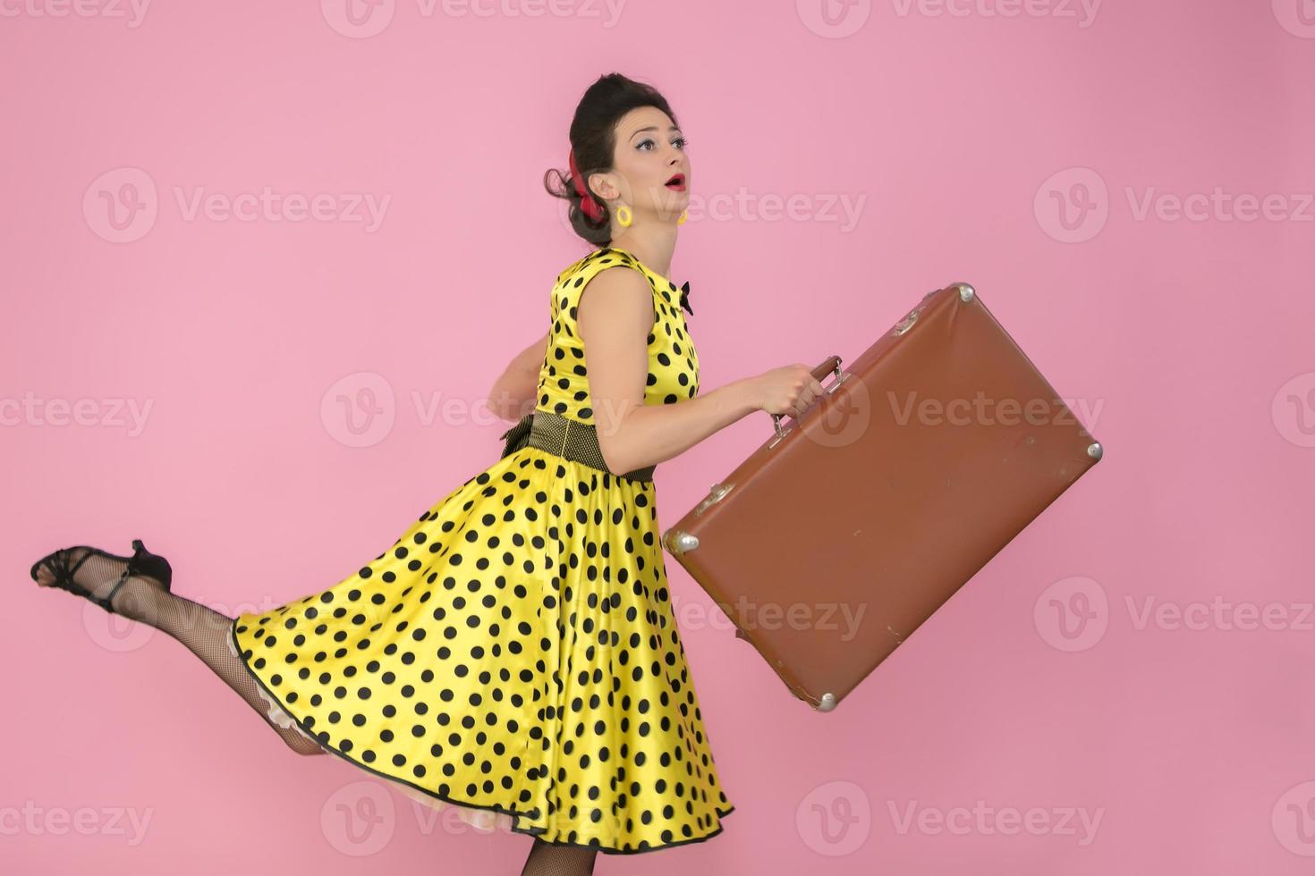 retro Mädchen mit ein alt Koffer auf ein Rosa Hintergrund. foto