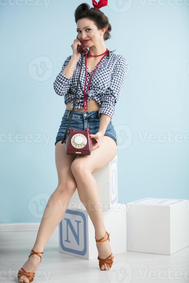 Frau im das Stil von das fünfziger Jahre. schön retro Frau mit ein Telefon auf ein Blau Hintergrund. foto