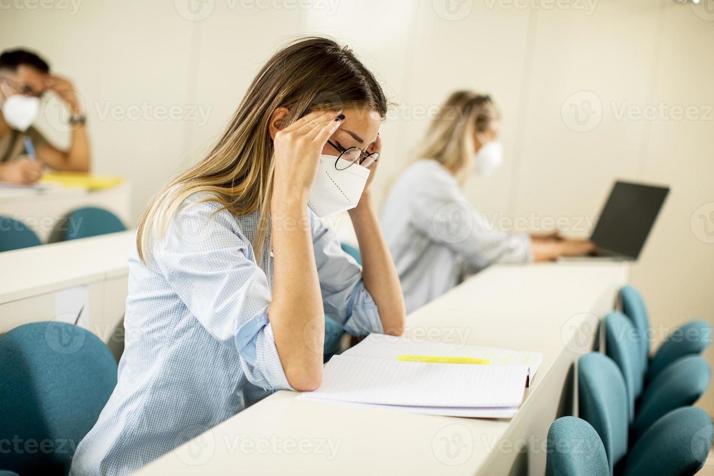 Studentin mit Gesichtsschutzmaske zum Virenschutz im Hörsaal foto