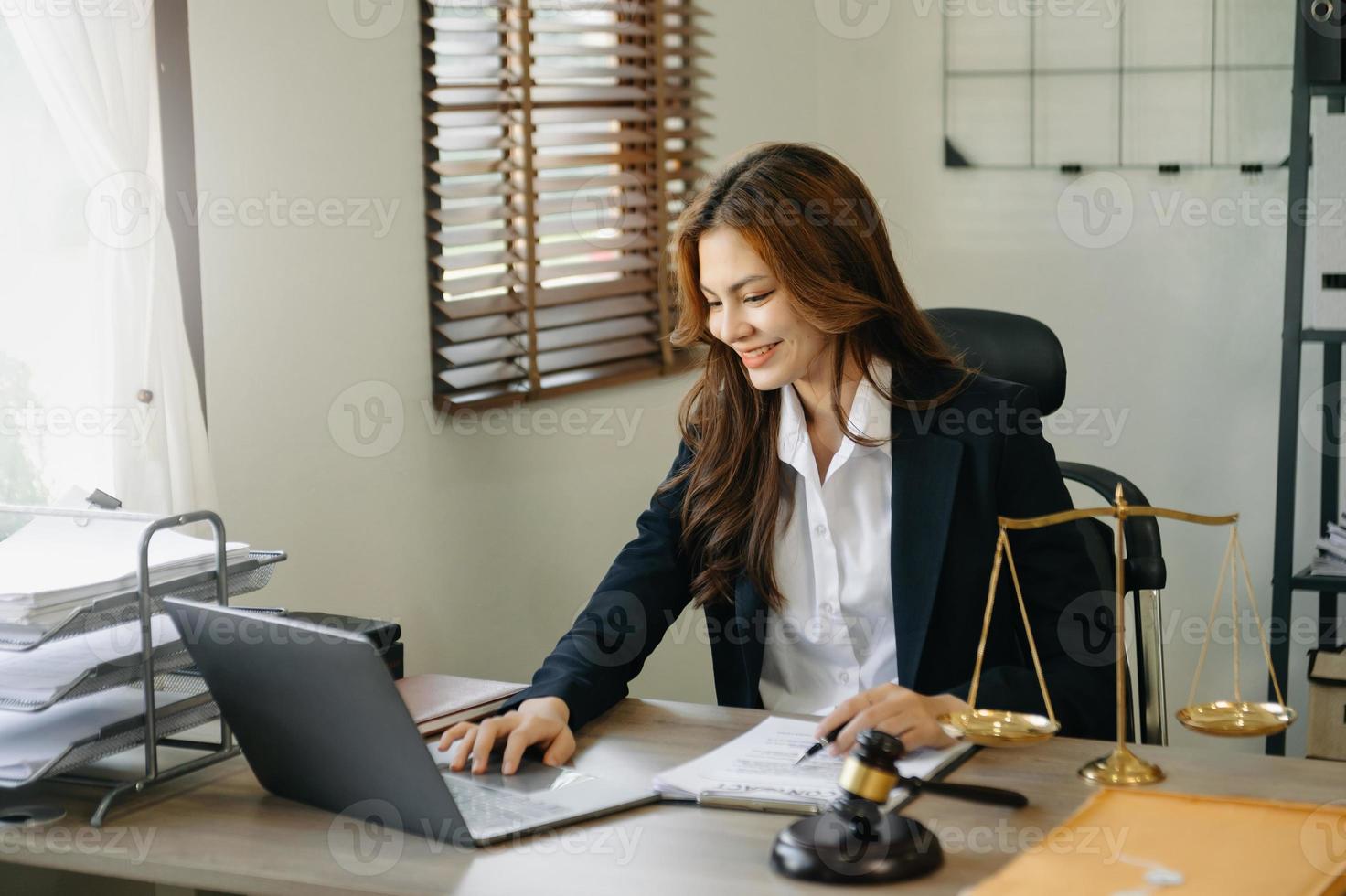 schöne asiatische rechtsanwältin, die arbeitet und hammer, tablette, laptop vorne, beratungsjustiz- und gesetzeskonzept. foto