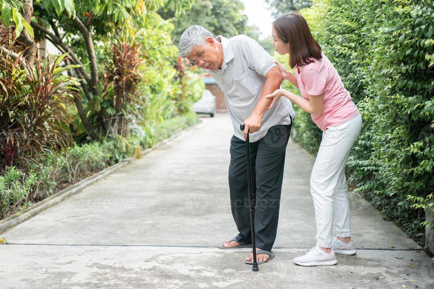 asiatisch Senior Mann Gehen im das Hinterhof und schmerzlich Entzündung und Steifheit von das Gelenke Arthritis und das Tochter kam zu Hilfe Unterstützung. Konzept von alt Alten Versicherung und Gesundheit Pflege foto