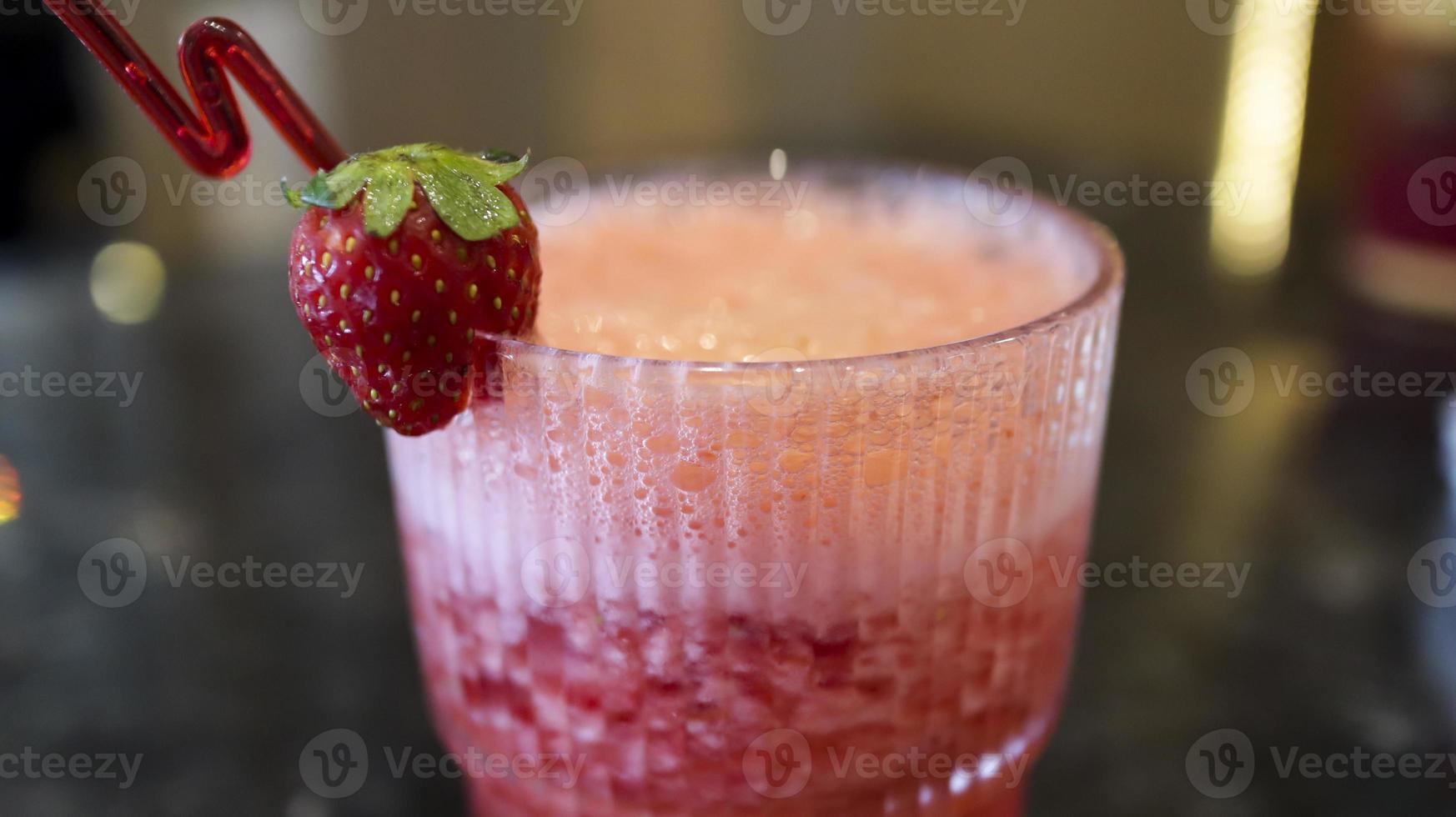 ein Glas von Erdbeere Saft beim das Tabelle mit ein schick Stroh. foto
