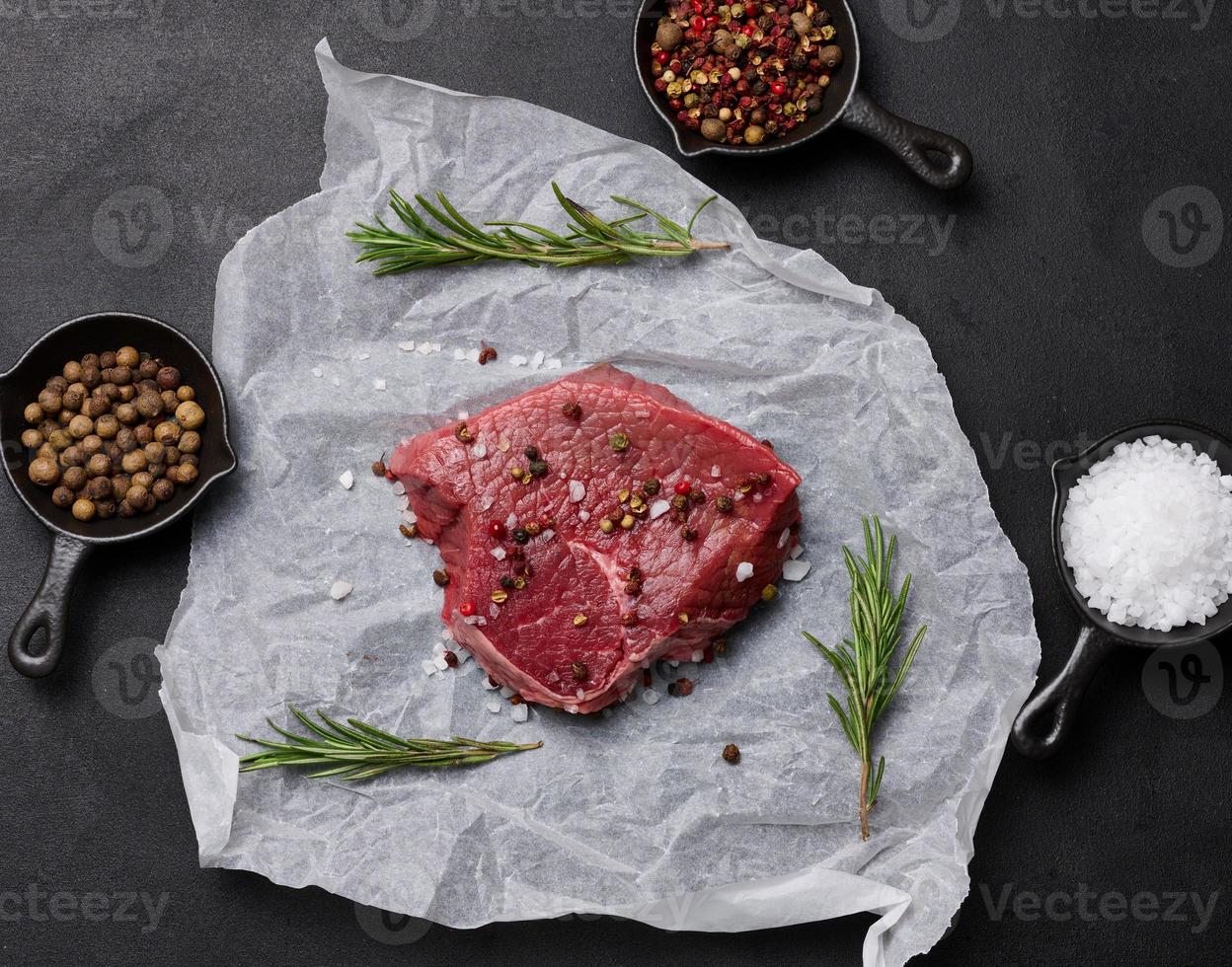 roh Stück von Rindfleisch mit Gewürze Lügen auf ein Weiß Stück von Pergament Papier, oben Aussicht foto