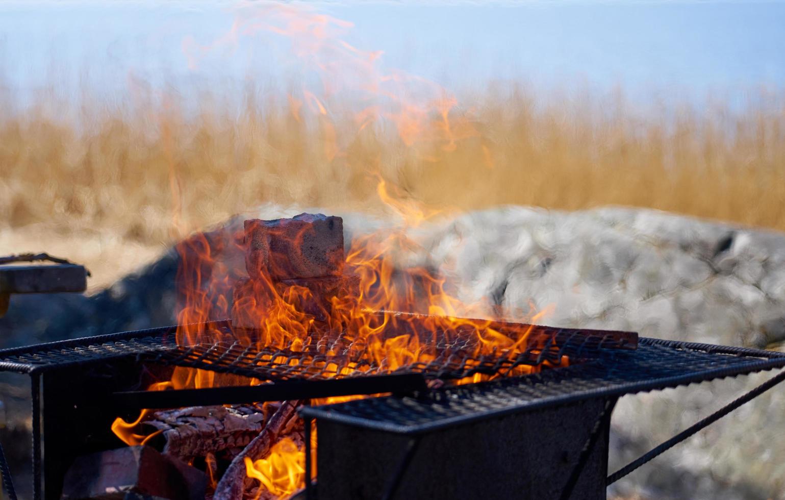 Feuer in einem rostigen Vintage-Grill im Freien am Strand des Meeres foto