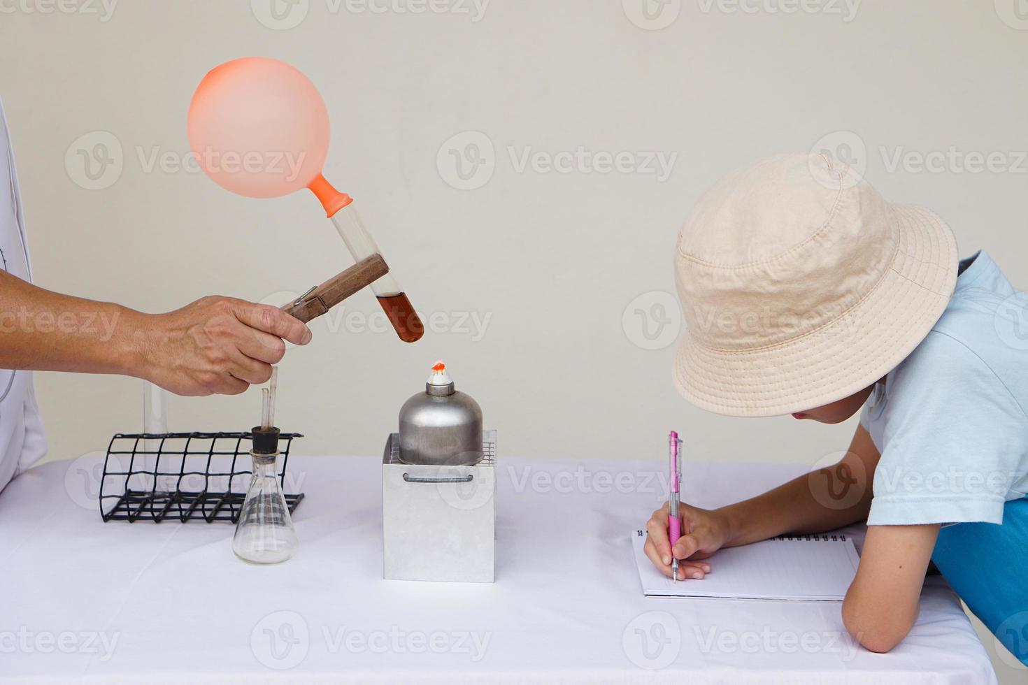 Schüler ist nehmen Hinweis Über Reaktion von Ballon auf Prüfung Tube ist verbrannt von Laterne. Konzept, Wissenschaft Experiment. das expandieren von Luft von Wasser Sieden. Lernen durch tun. foto