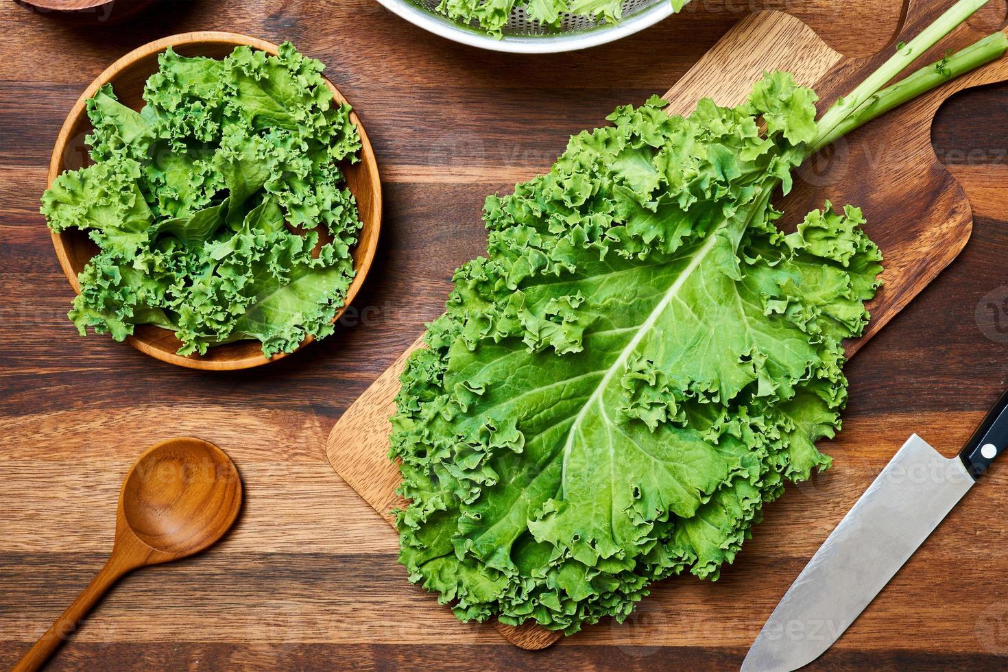 Konzept von frisch Grünkohl Blätter Salat auf hölzern Tabelle Hintergrund. vorbereiten Grün Grünkohl Blätter Salat Essen im das Küche. eben legen, oben Aussicht foto