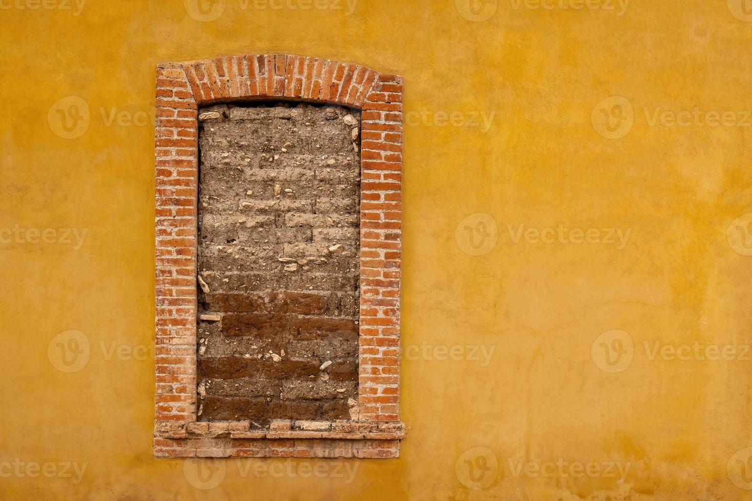 ein Gelb Mauer mit ein Fenster Das hat ein Backstein Bogen und ein Backstein Rahmen Das sagt "alt". Es. foto