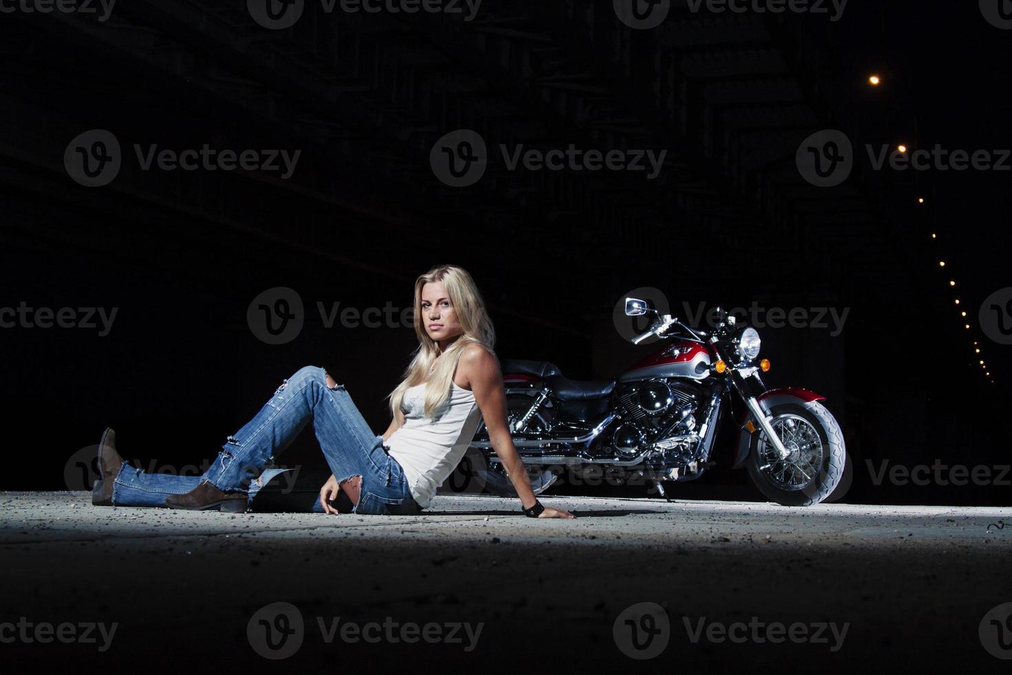 sexy Blondine sitzt in der Nähe ihres Motorrades foto