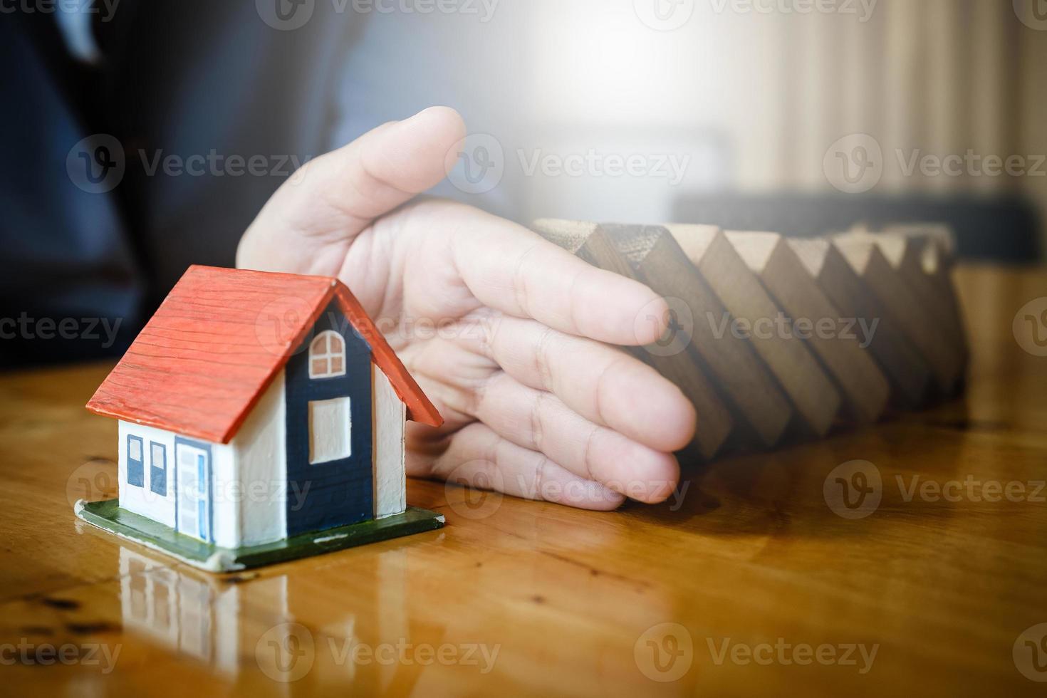 Schließen Sie Geschäftsfrau mit der Hand zwischen einem Haus und Holzklötzen, um das Risiko von allem, Sicherheit und Versicherungskonzept zu stoppen. foto