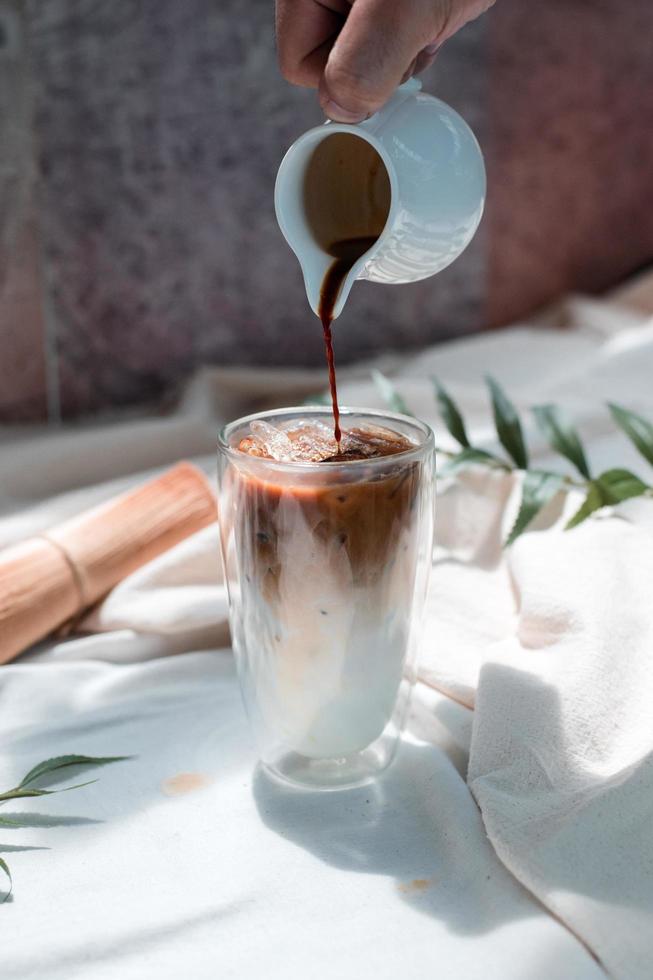 Barista gießt Milch in ein Glas Eiskaffee foto