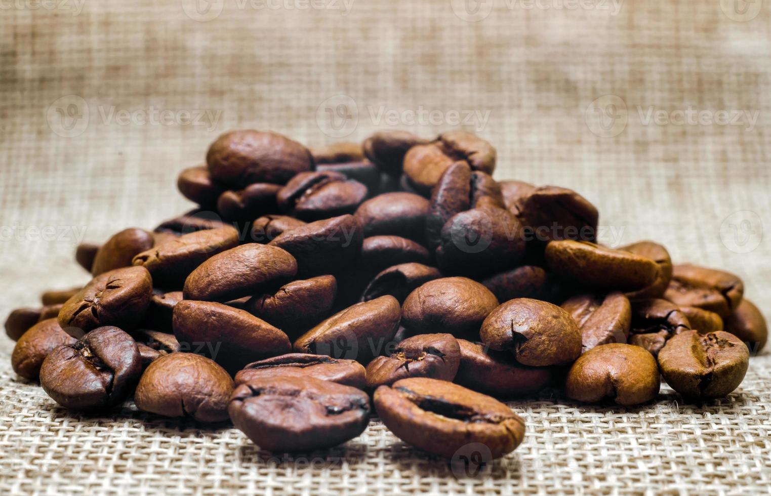 Haufen von Kaffeebohnen auf einer Mattierung, Makrobeige Hintergrundnahaufnahme foto