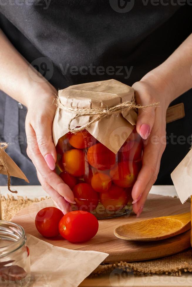 junge Frau, die ein Glas eingelegtes Gemüse hält. Fermentationsprozess von Tomaten. gesundes Öko-Essen. foto