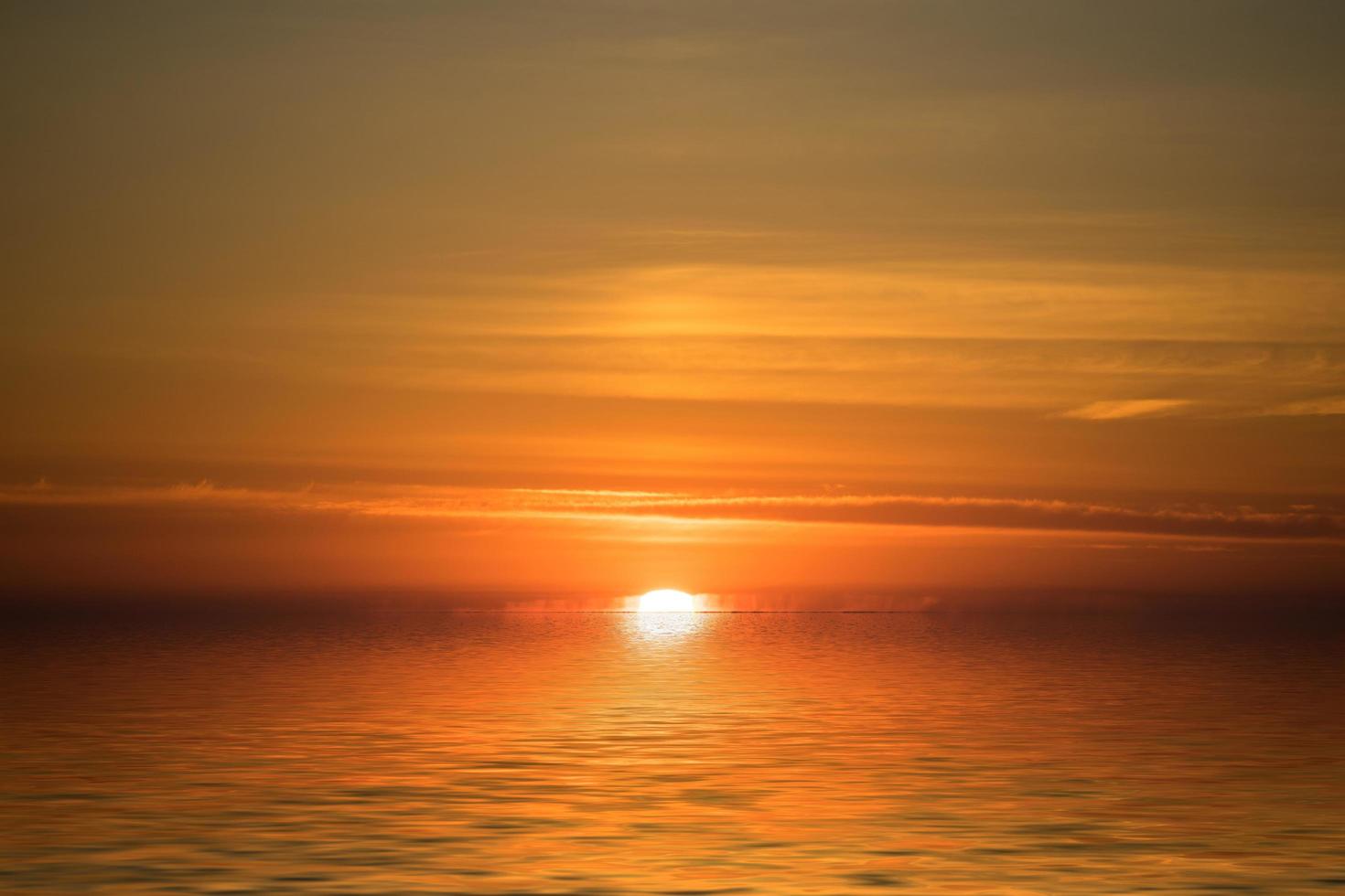 bunter bewölkter orange Sonnenuntergang mit Blick auf ein Gewässer foto