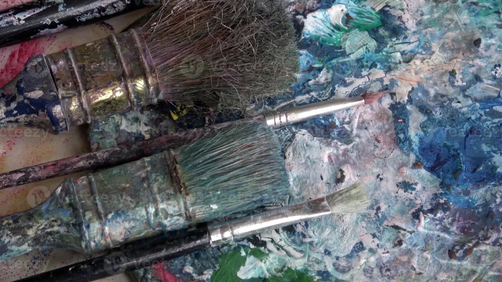 gebrauchte Pinsel auf einer Künstlerpalette mit bunter Ölfarbe foto