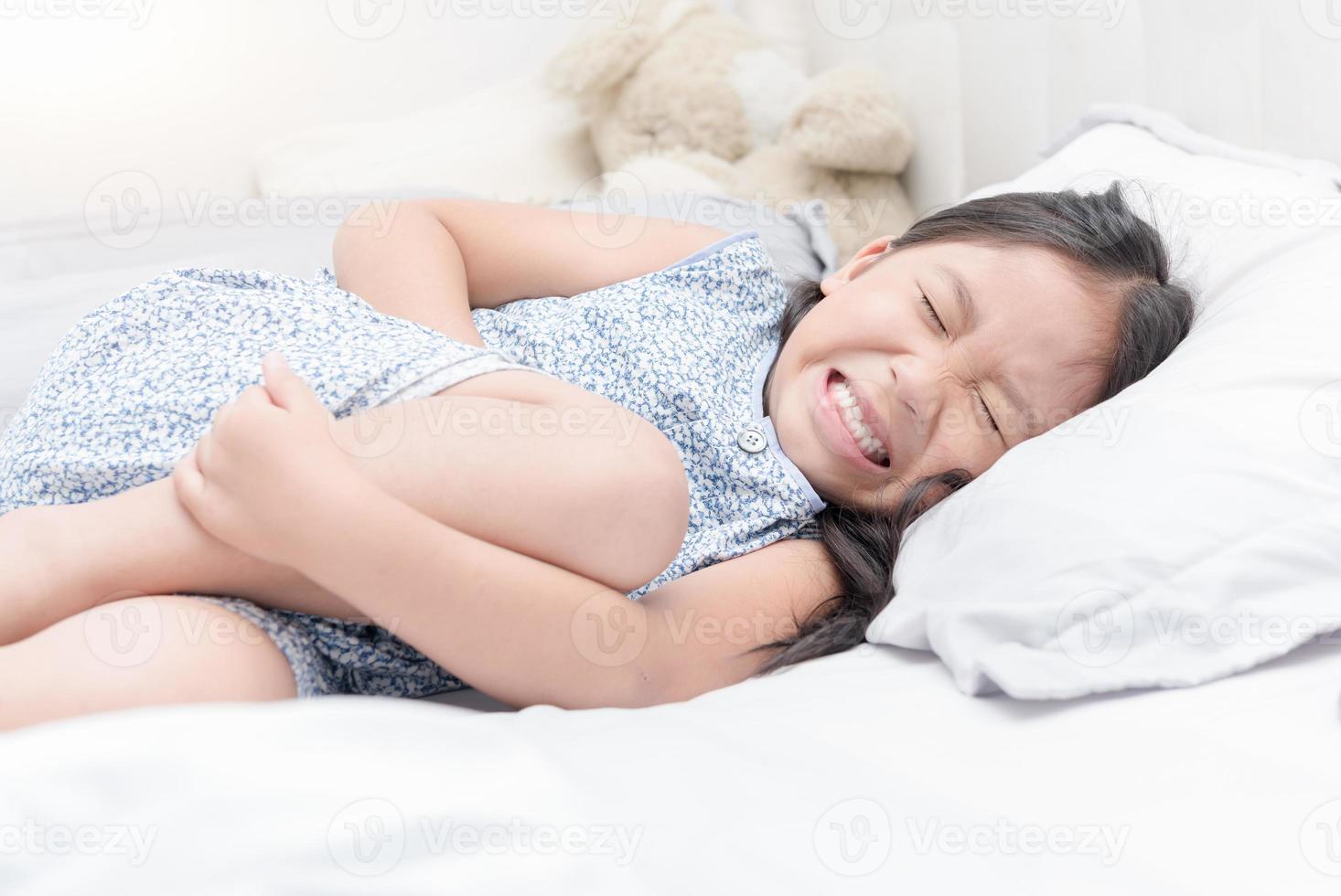 asiatisch Mädchen Gefühl Magenschmerzen Schmerzen auf Bett, foto