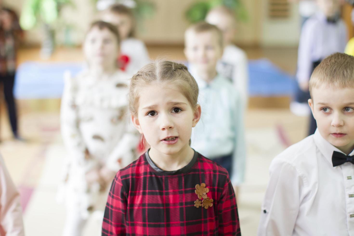 das Gesicht von ein Mädchen von elementar Alter gegen das Hintergrund von andere Kinder. foto