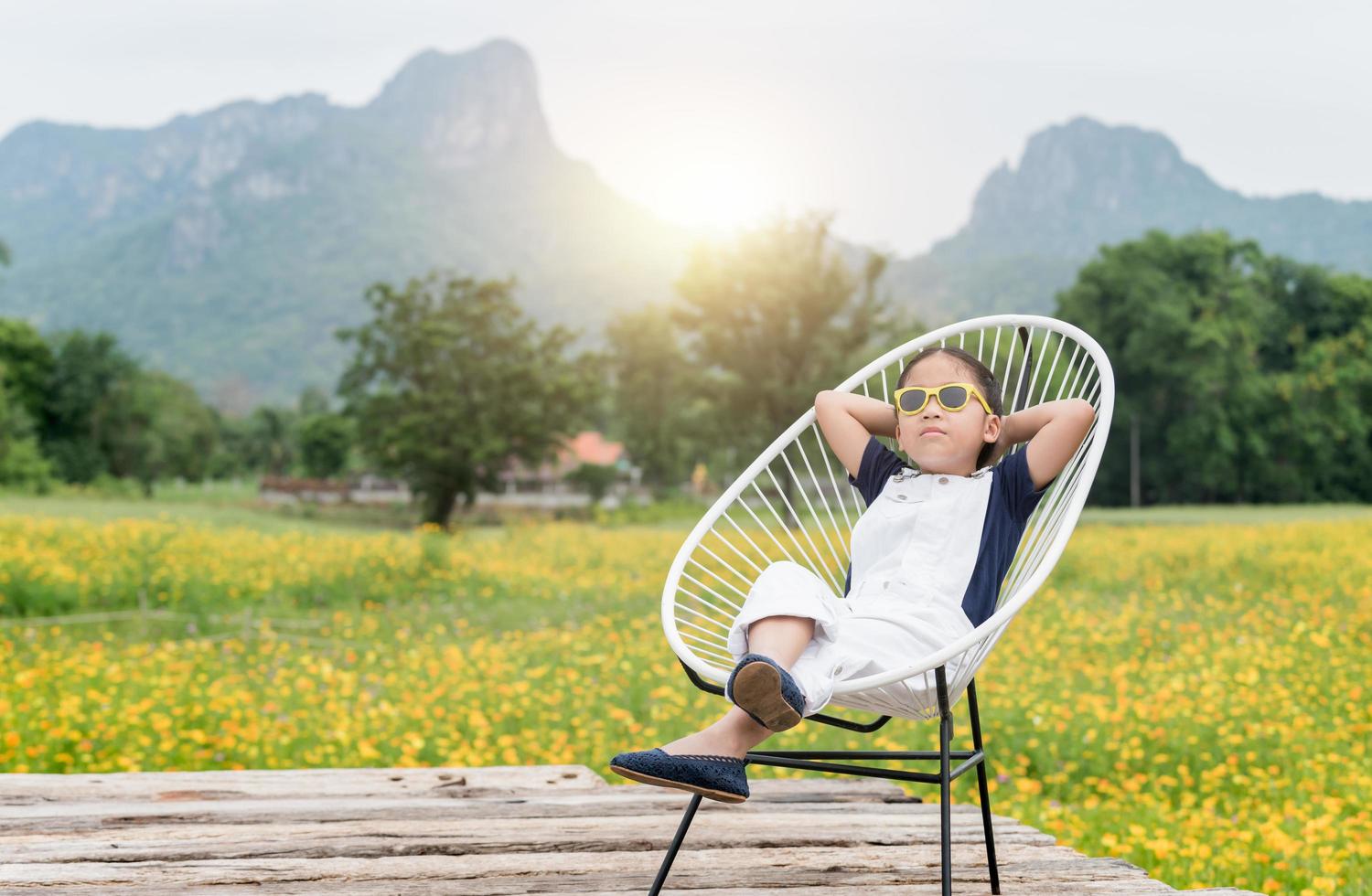 süß Mädchen sitzen und entspannen auf Stuhl und Gelb Blume Hintergrund foto