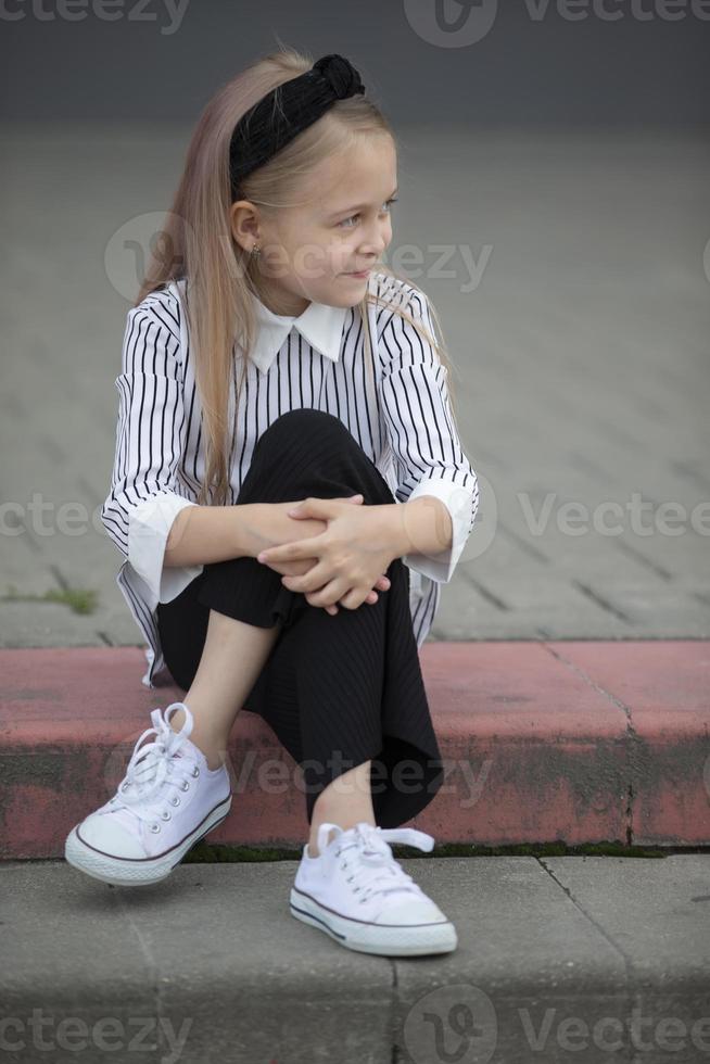 ein Kind im ein städtisch Umfeld. ein Vorschulalter Mädchen sitzt auf das Schritte. foto