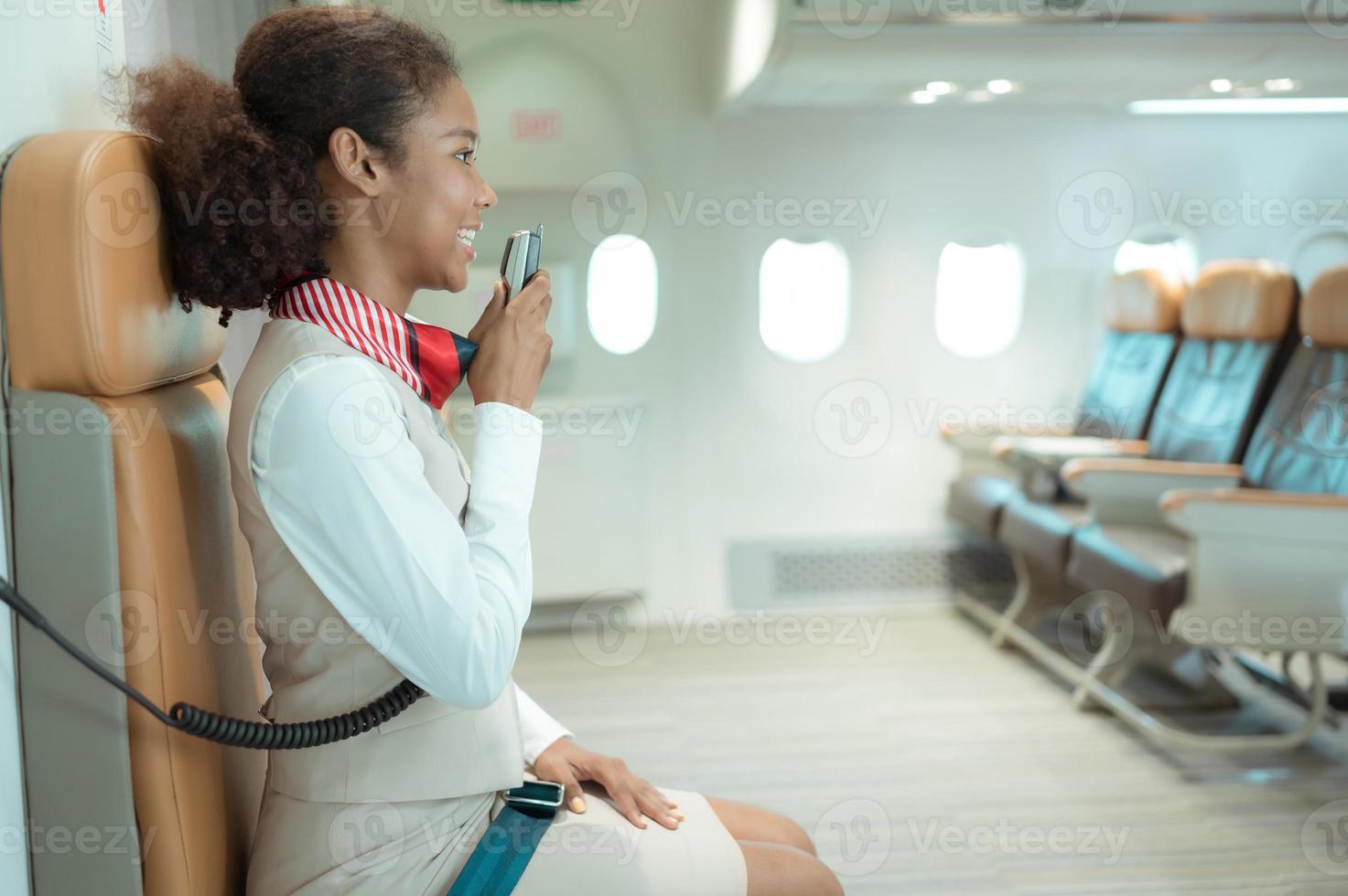 Flug Begleiter Sprechen durch ein Lautsprecher zu herzlich willkommen Passagiere und geben Rat auf Reisen durch Flugzeug foto