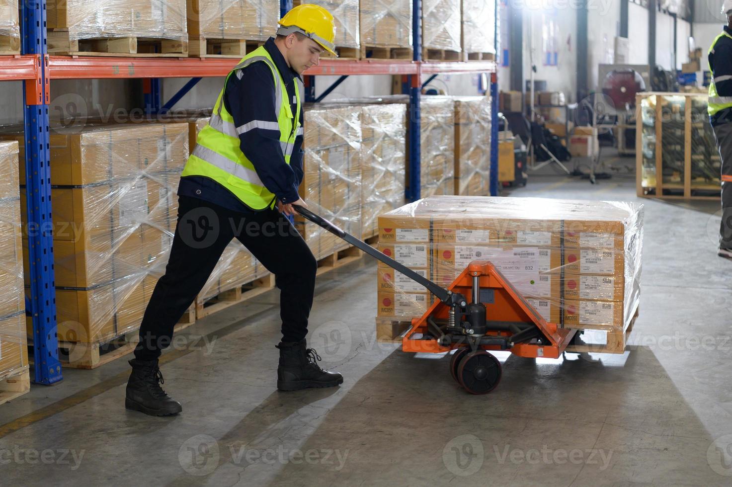 Arbeiter im Auto Teile Warenhaus verwenden ein Handwagen zu Arbeit zu bringen das Box von Auto Teile in das Lager Regal von das Warenhaus warten zum Lieferung zu das Auto Versammlung Linie foto