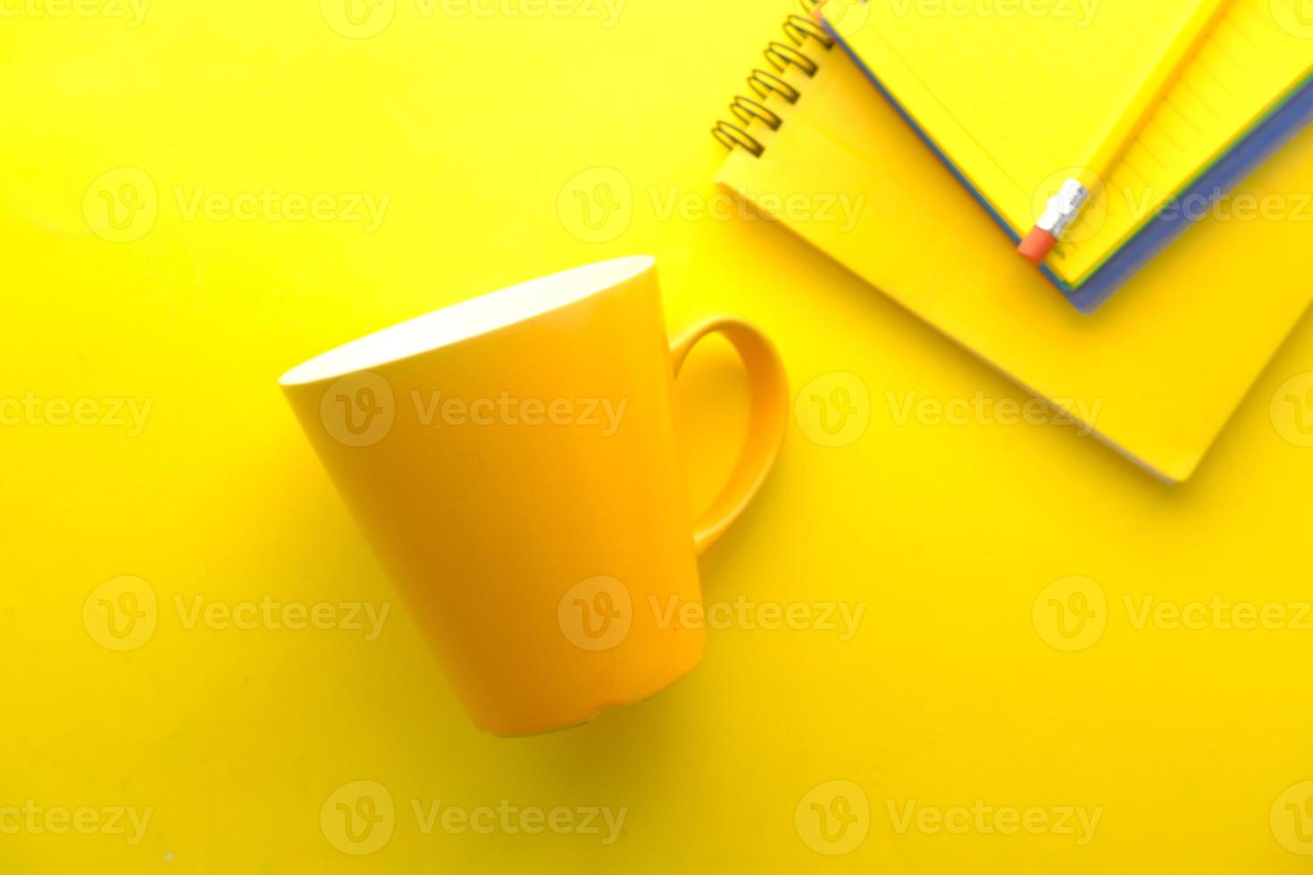 gelber Becher und Notizbücher auf gelbem Hintergrund foto