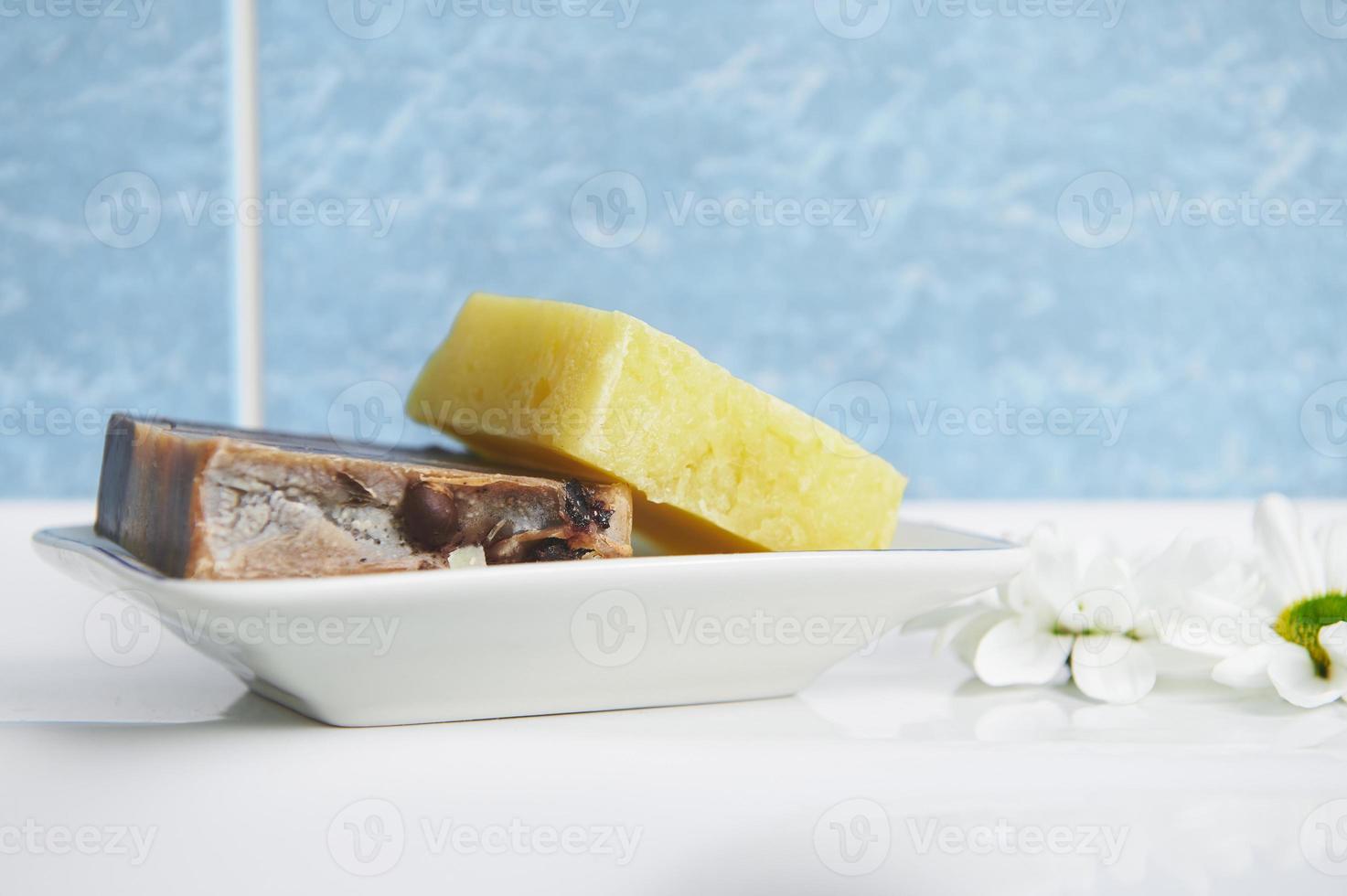 Nahansicht von natürlich organisch Kunst Seife Riegel auf das Seife Halter gegen Blau Marmor Badezimmer Mauer Hintergrund foto