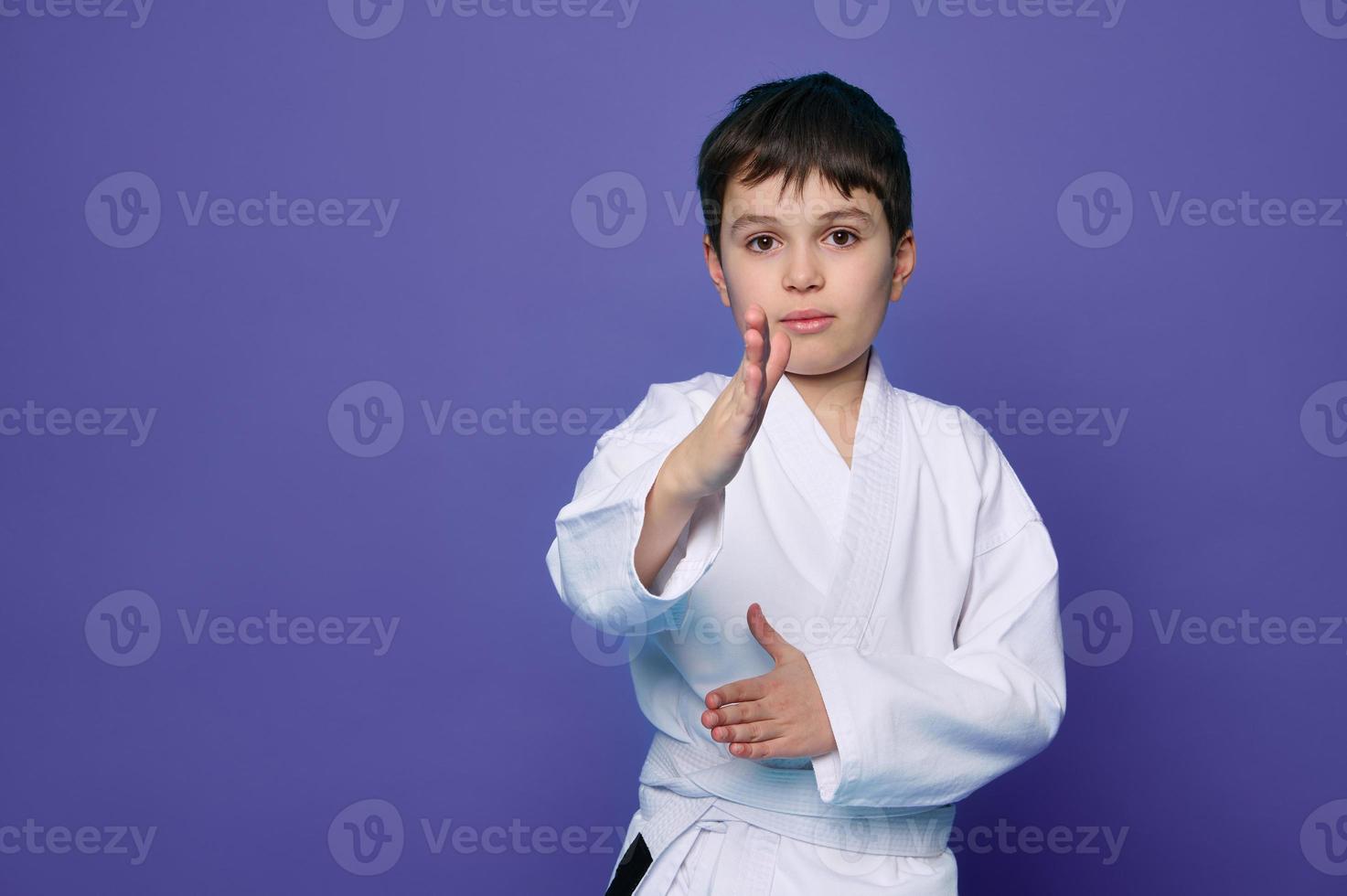 kriegerisch Kunst Attacke. Schule Alter Junge Aikido Kämpfer im Weiß Kimono isoliert Über lila Hintergrund mit Kopieren Raum zum Werbung Text. foto