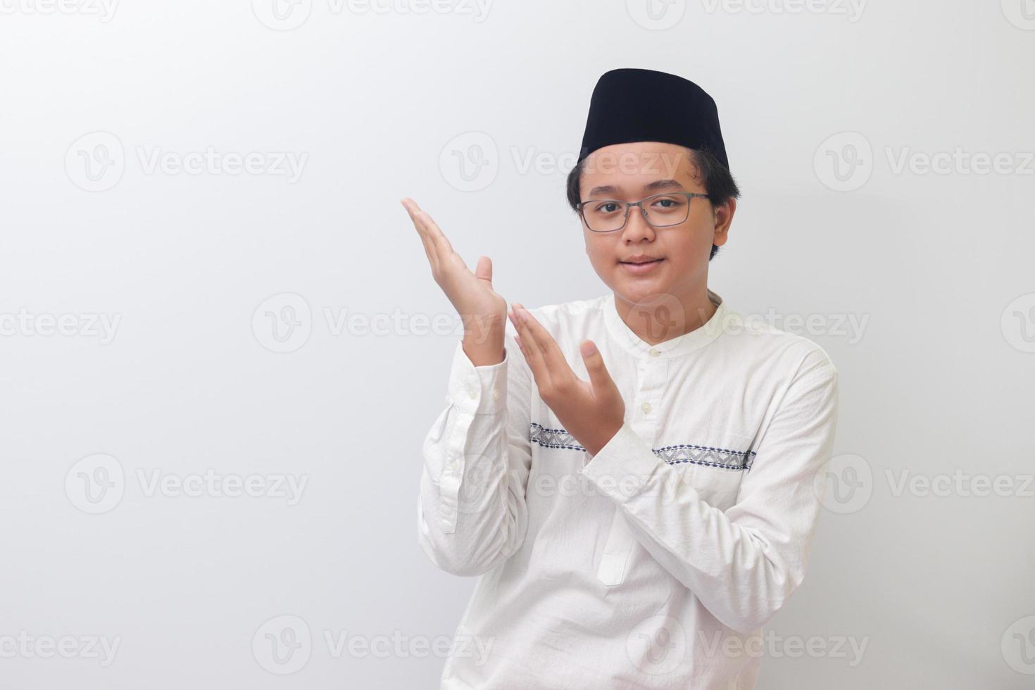 Porträt von jung asiatisch Muslim Mann zeigen Produkt und zeigen mit seine Hand und Finger. isoliert Bild auf Weiß Hintergrund foto