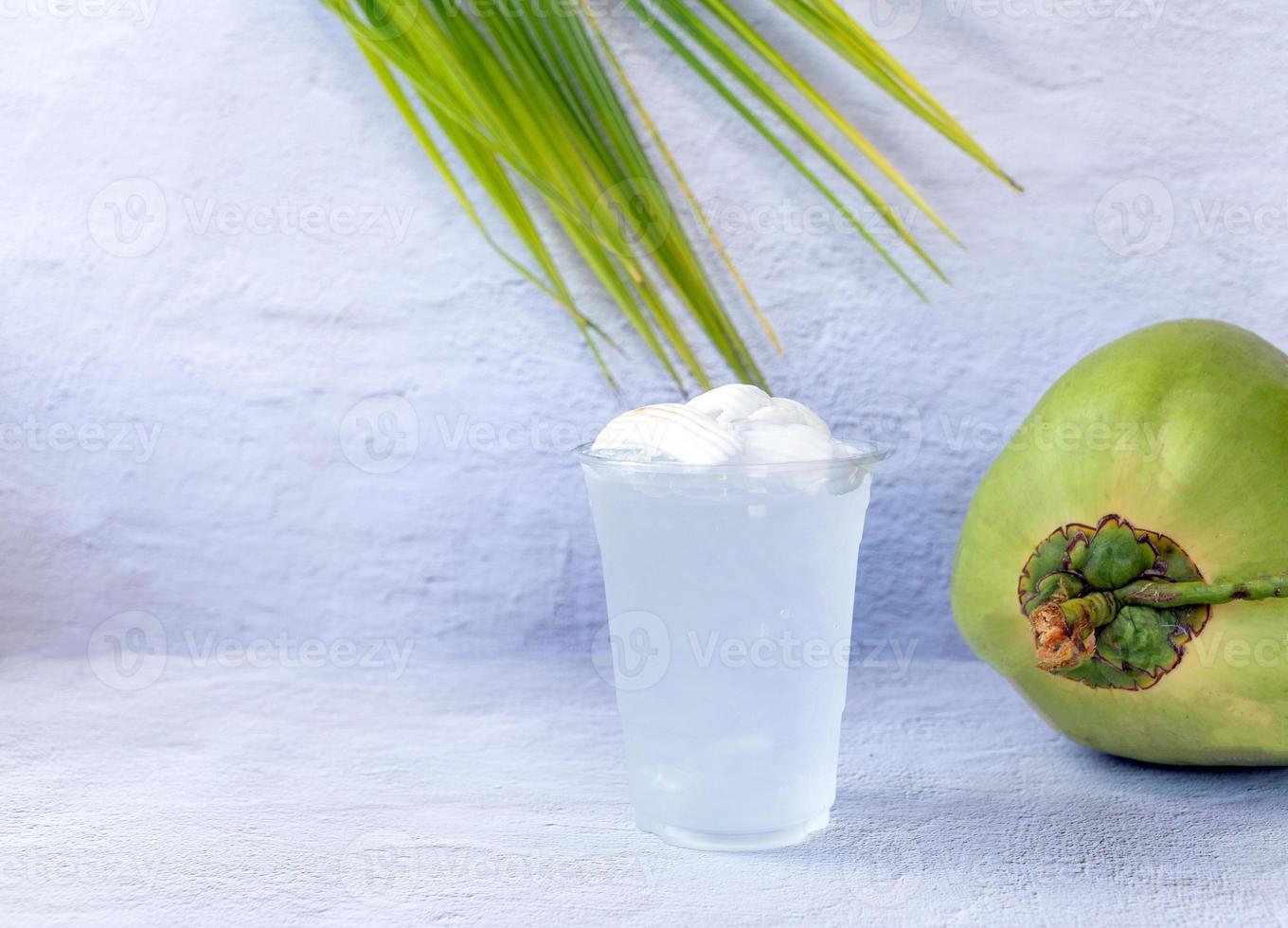 Eis-Kokoswassergetränk in einem Plastikglas und in einer Kokosnuss auf weißem Hintergrund foto