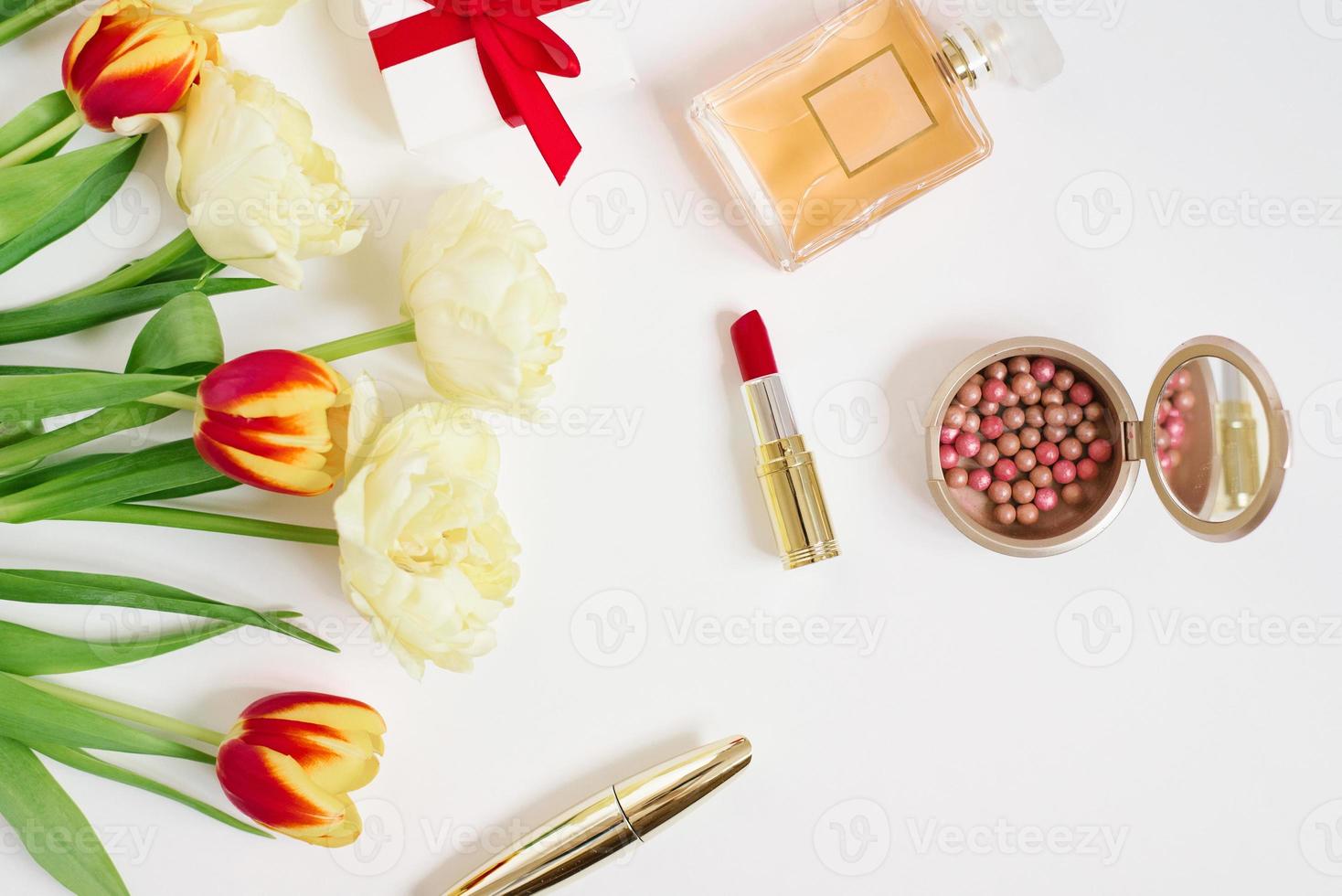 rote und gelbe tulpen in einer roten geschenktüte, kosmetik und geschenk auf weißem hintergrund mit kopierraum. grußkarte zum valentinstag oder muttertag. stilvolle Blogger-Wohnung foto