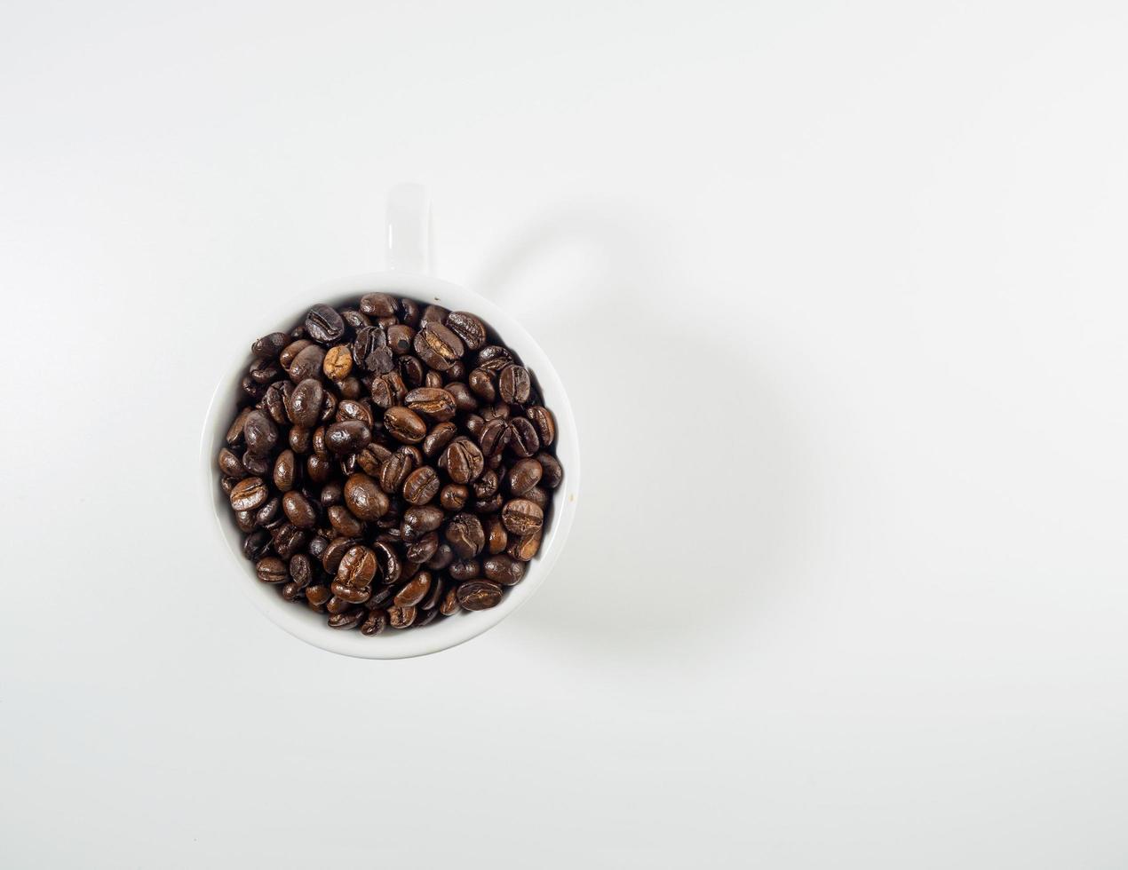 geröstet Arabica Kaffee Bohnen, bereit zu machen Kaffee Das Menschen mögen zu trinken. platziert im ein Weiß Kaffee Tasse auf das Hintergrund. sieht aus schön und appetitlich. trinken. foto