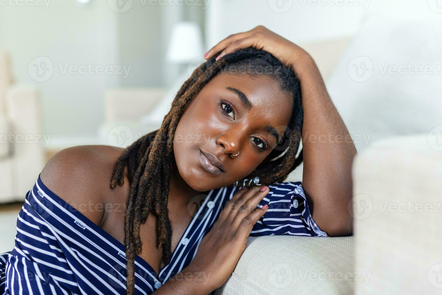 Porträt von ein schön Frau lächelnd beim heim. afrikanisch Frau im beiläufig suchen beim Kamera mit Kopieren Raum. heiter gemischt Rennen Mädchen entspannend beim Zuhause foto