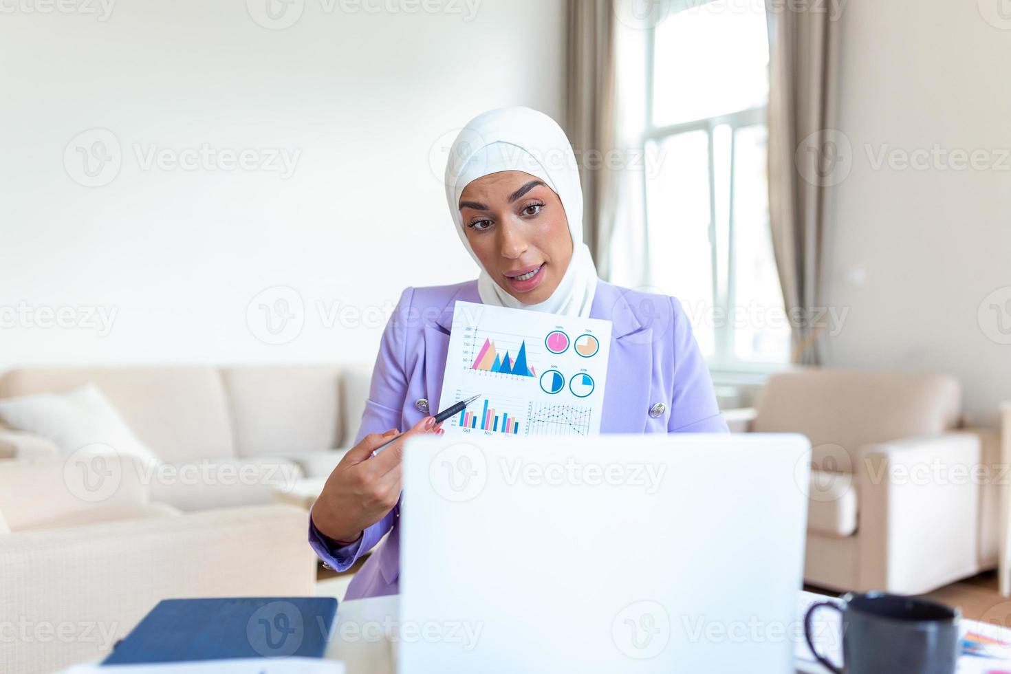 konzentriert Muslim Geschäftsfrau präsentieren Diagramme und Grafiken auf Video Anruf online. jung Geschäft Frau ich h Hijab haben Konferenz Anruf mit Klient auf Laptop. Arbeiten Laptop Computer drinnen. foto