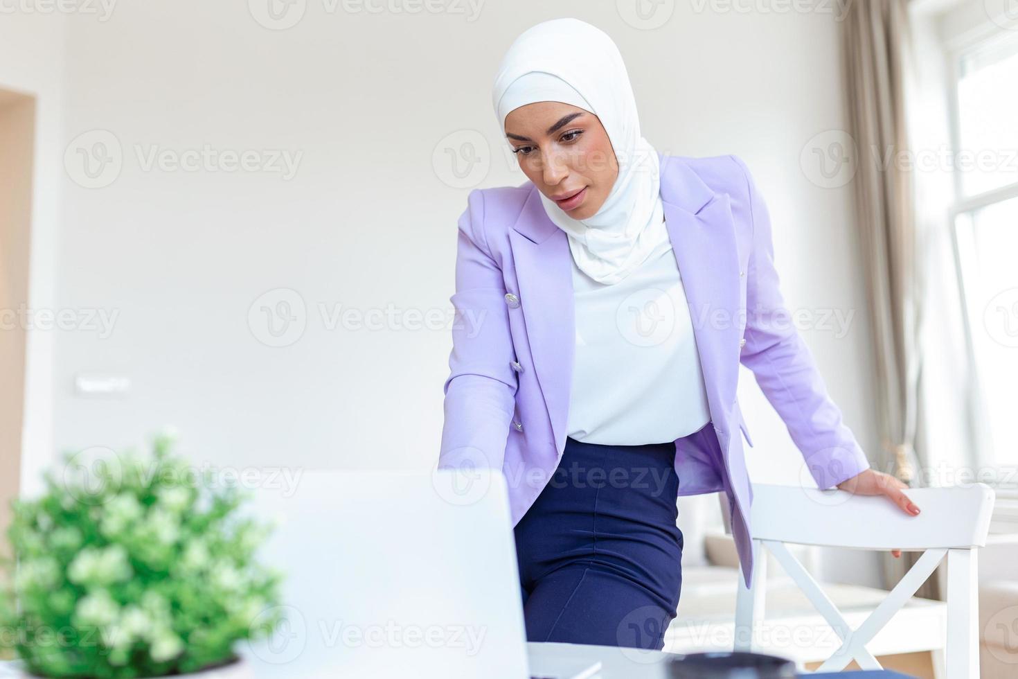 Muslim Frau Arbeiten mit Computer beim heim. Muslim Frau Arbeiten mit Computer im das Zimmer , Schreiben Papier. Vertrauen ziemlich Muslim Frau Geschäft und Finanzen Konzepte. foto