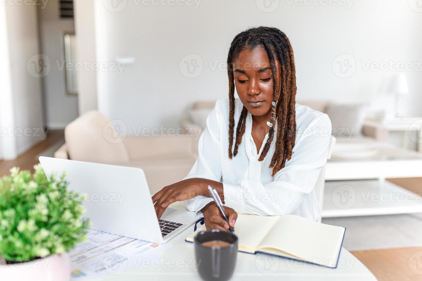 Fernbedienung Arbeit, Technologie und Menschen Konzept - - jung afrikanisch Geschäft Frau mit Laptop Computer und Papiere Arbeiten beim Zuhause Büro während das covid-19 Gesundheit Krise. foto