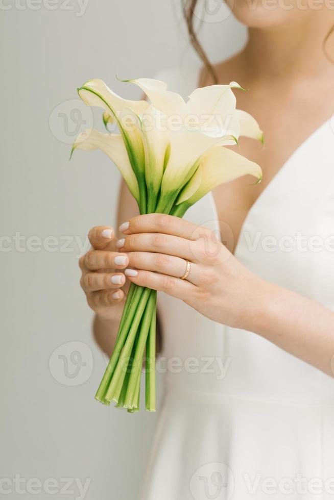 Weißer Brautstrauß aus Calla-Lilien in den Händen der Braut foto
