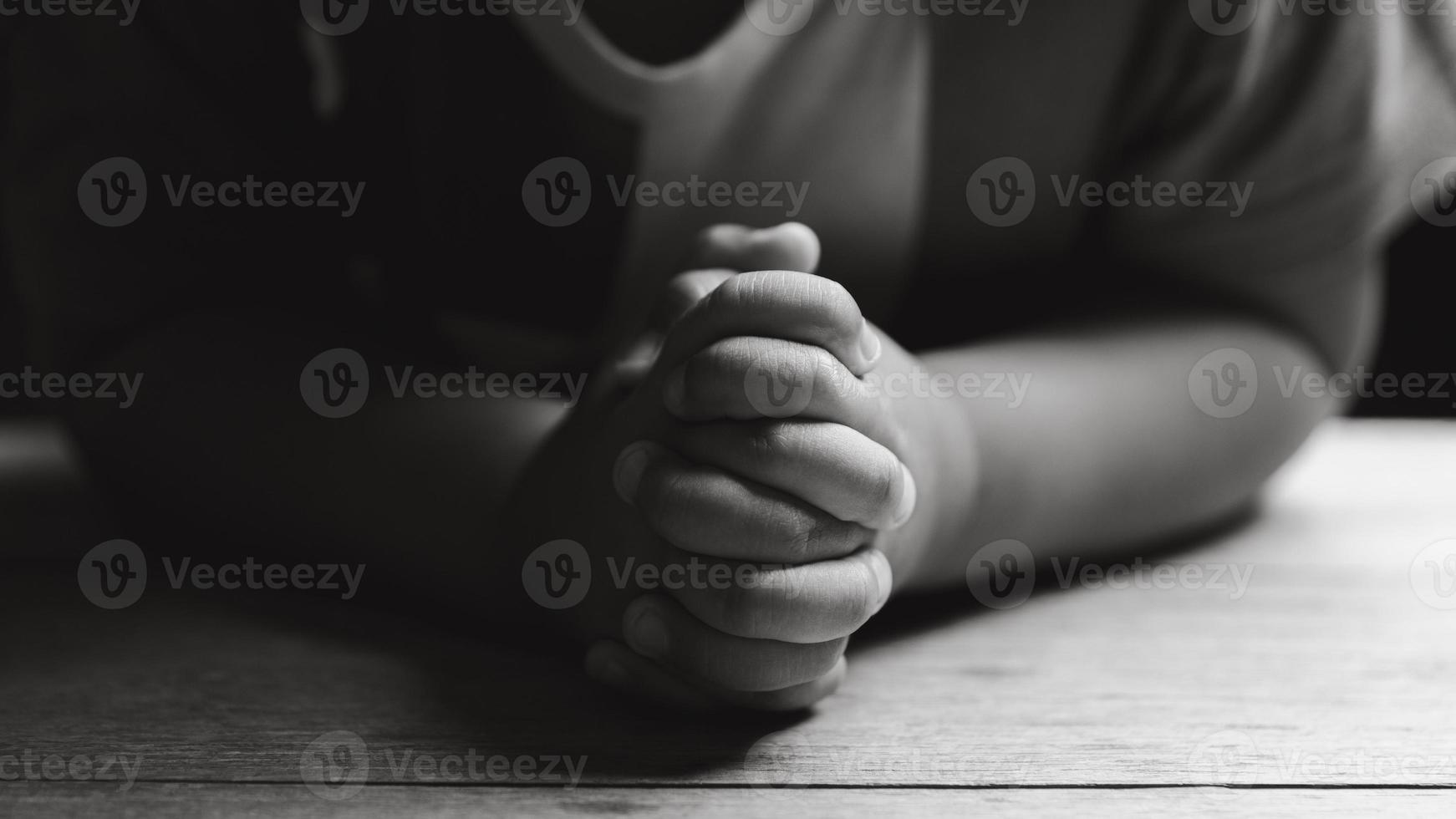 wenig Junge beten zu Gott mit Hände gehaltenen zusammen. Kind Anbetung zu Gott. süß wenig Junge im ein Christian Familie. foto