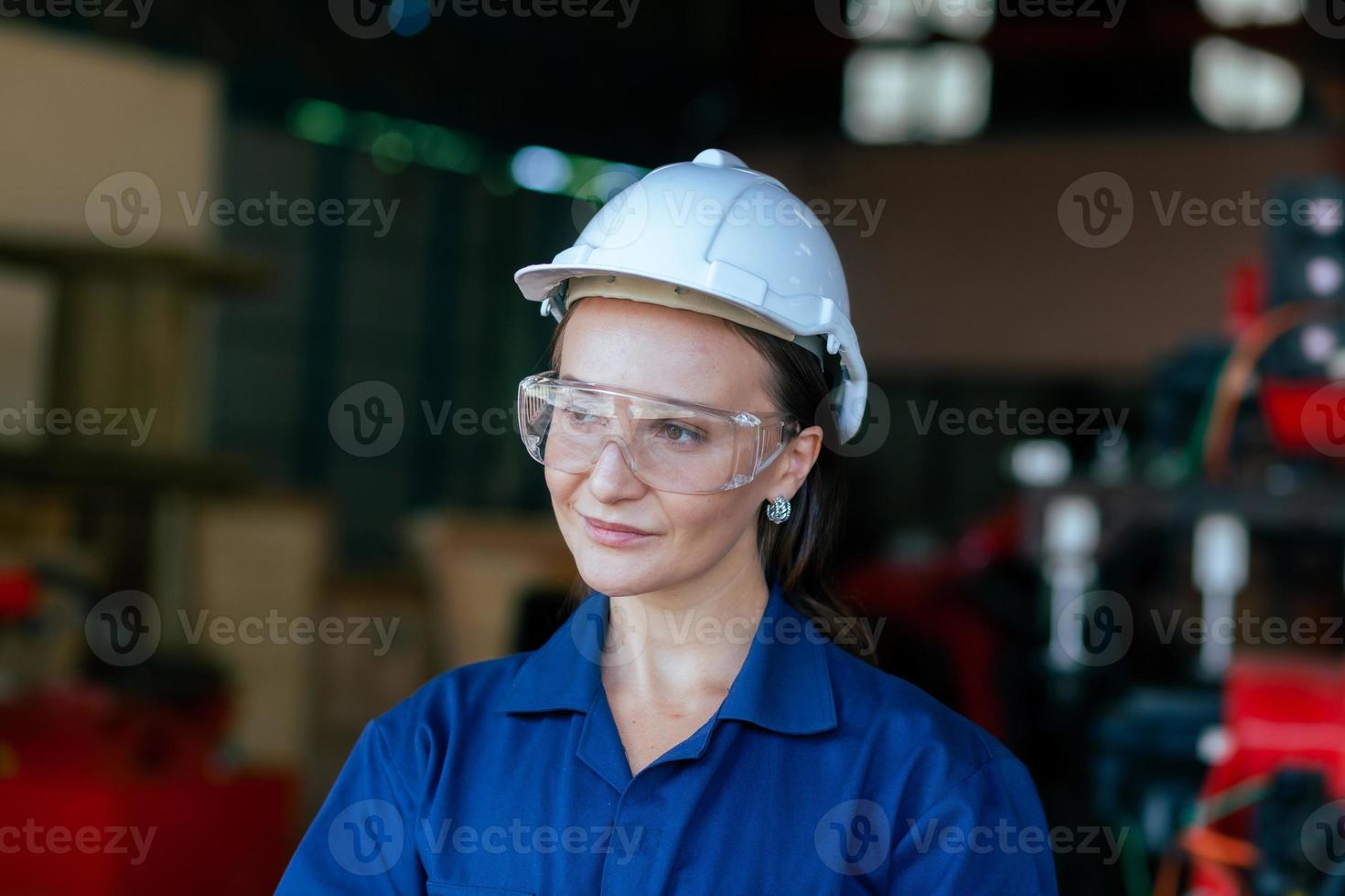 ein glücklich jung Frau Arbeiter von ein groß Maschinen Instandhaltung Fabrik im ein Blau Kleid und ein Weiß schützend Hut. Instandhaltung Wartung. Fabrik Sicherheit. Banner Bild foto