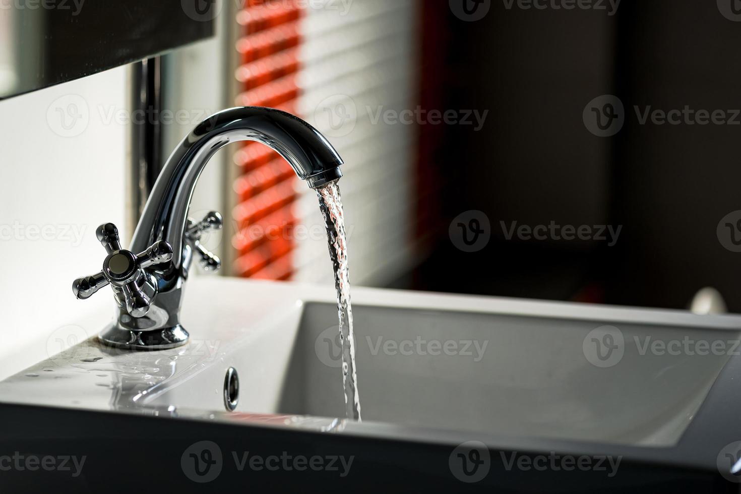 Wasserhahn und Wasser fließen auf Badezimmer foto