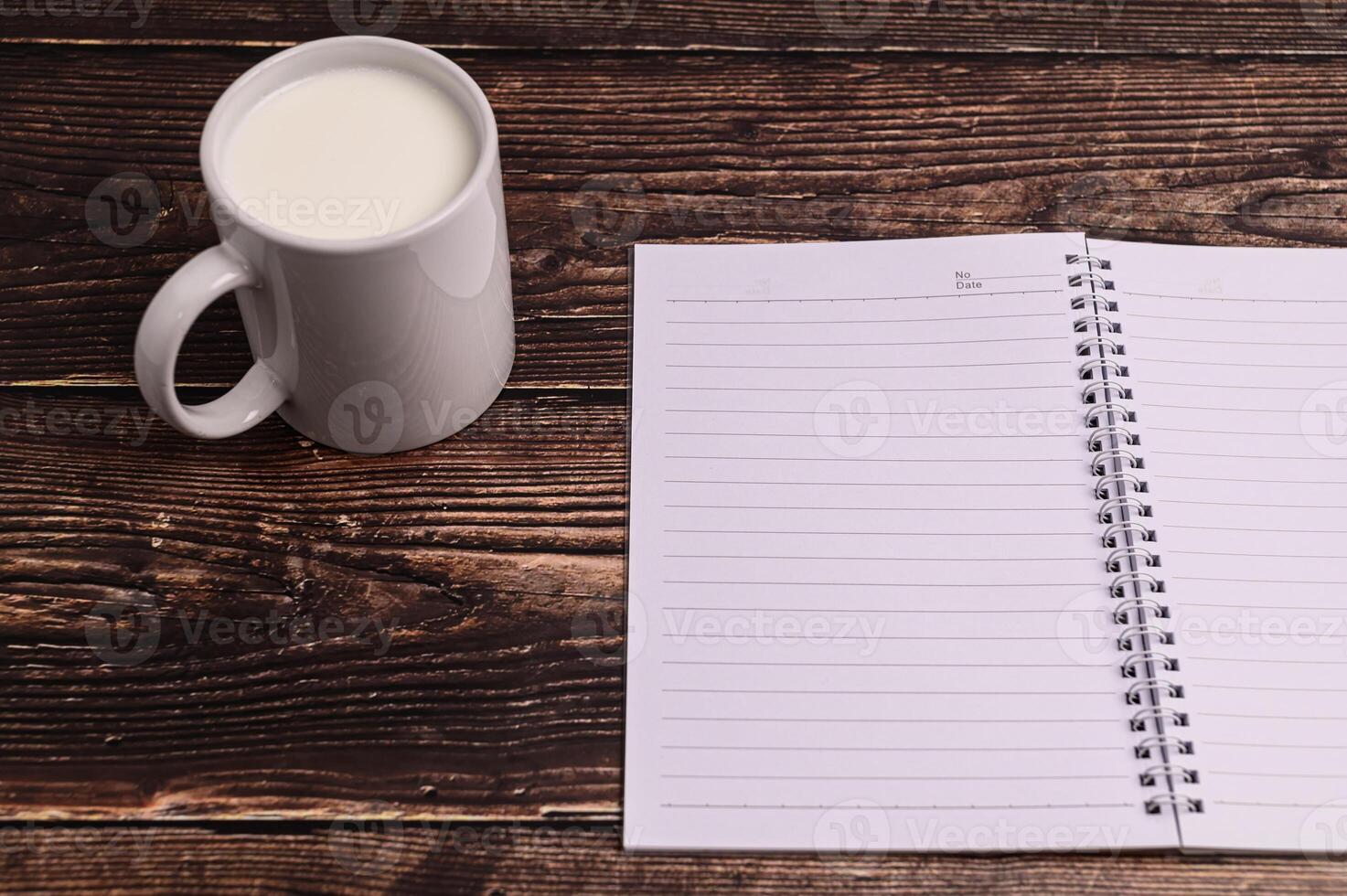 Notizbuch und ein Glas Milch auf dem Schreibtisch foto