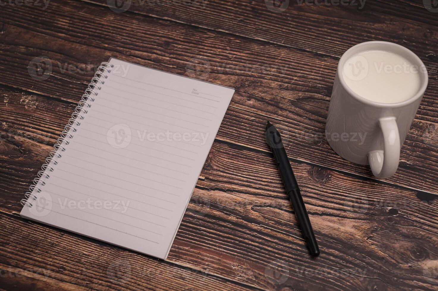 Notizbuch und ein Glas Milch auf dem Schreibtisch foto