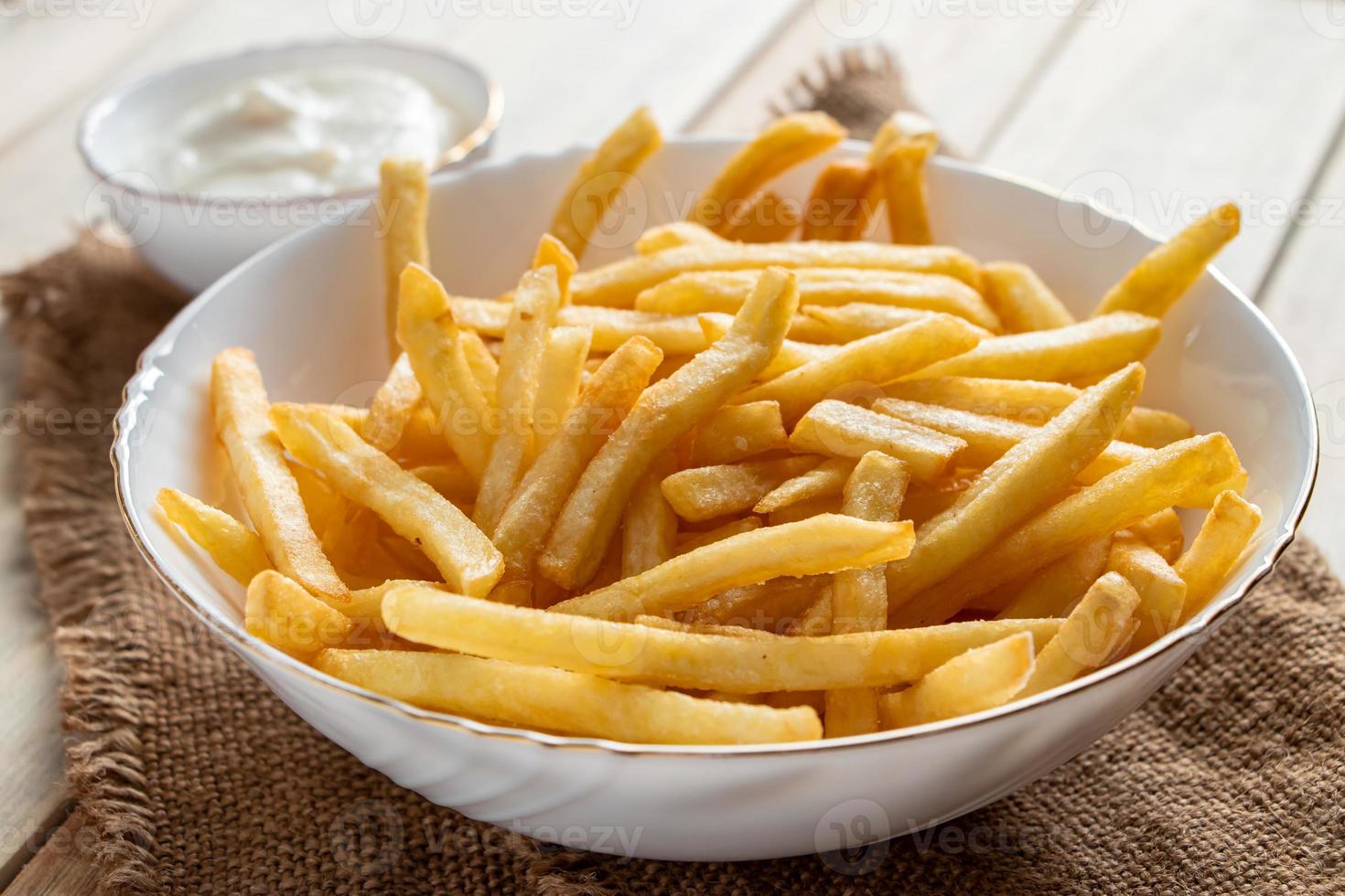 heiße goldene Pommes Frites mit Soße auf hölzernem Hintergrund foto