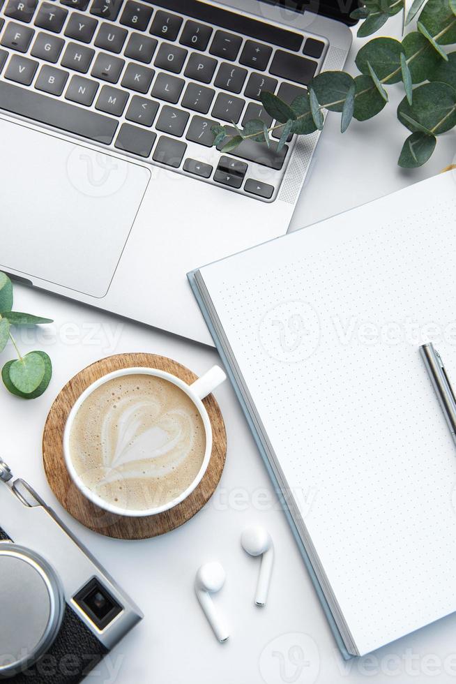 Schreibtisch mit Laptop, Kaffee, Notizbuch und Kamera foto