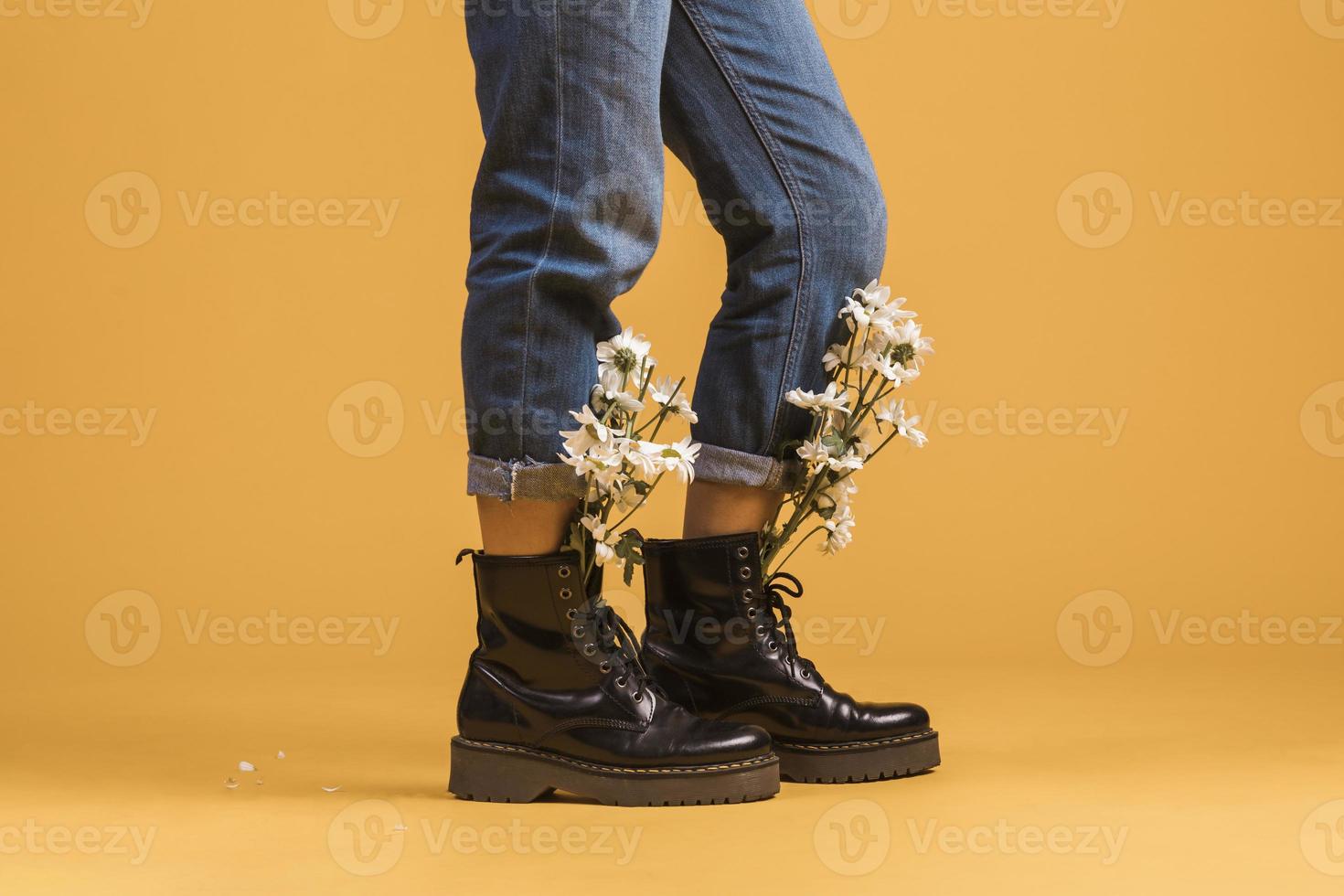 Frauenbeine, die Stiefel mit Blumen innen auf orange Hintergrund tragen foto