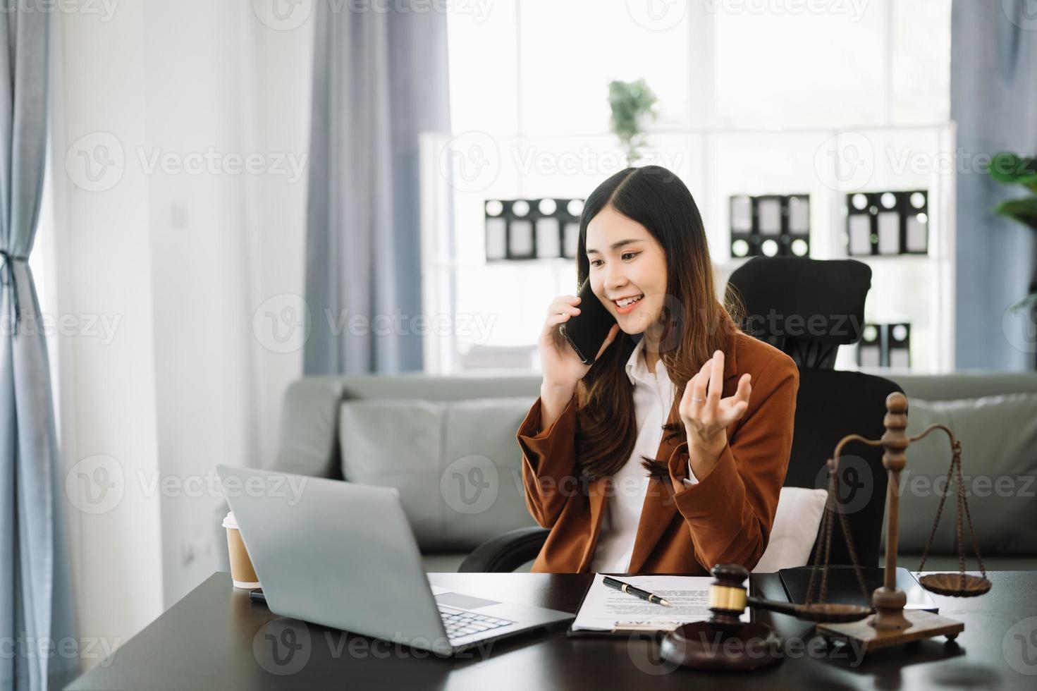 asiatisch weiblich Anwalt chatten online mit Klient auf Laptop, Smartphone diskutieren Einzelheiten von Klage. im modern Büro foto