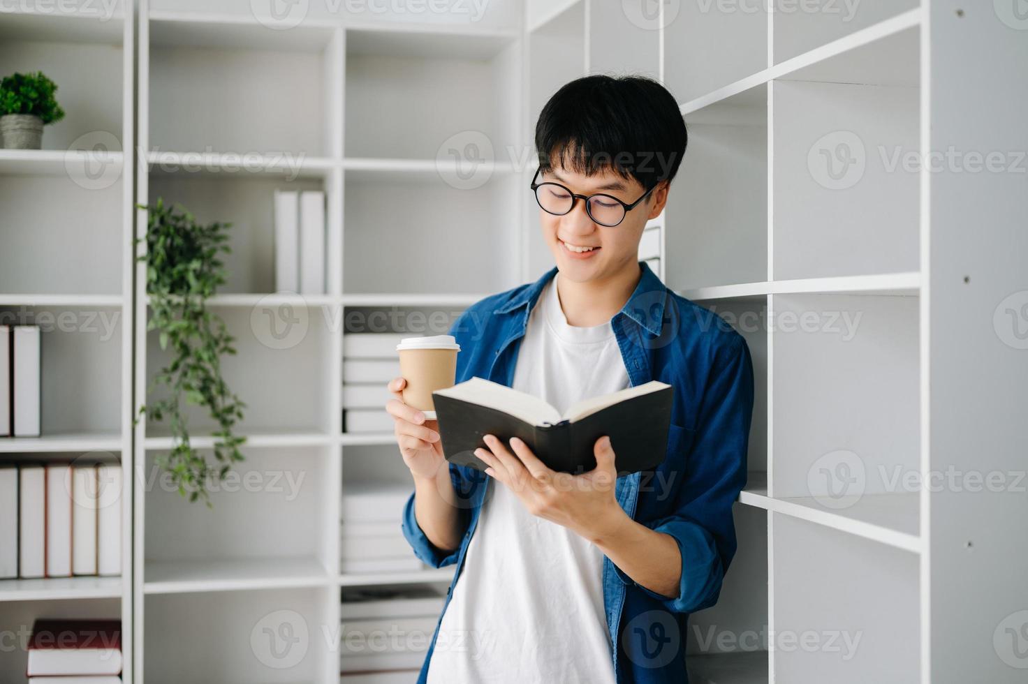 männlich Schüler nehmen Anmerkungen von ein Buch beim Bibliothek, jung asiatisch Sitzung beim Schreibtisch tun Zuordnungen im Hochschule Bibliothek foto